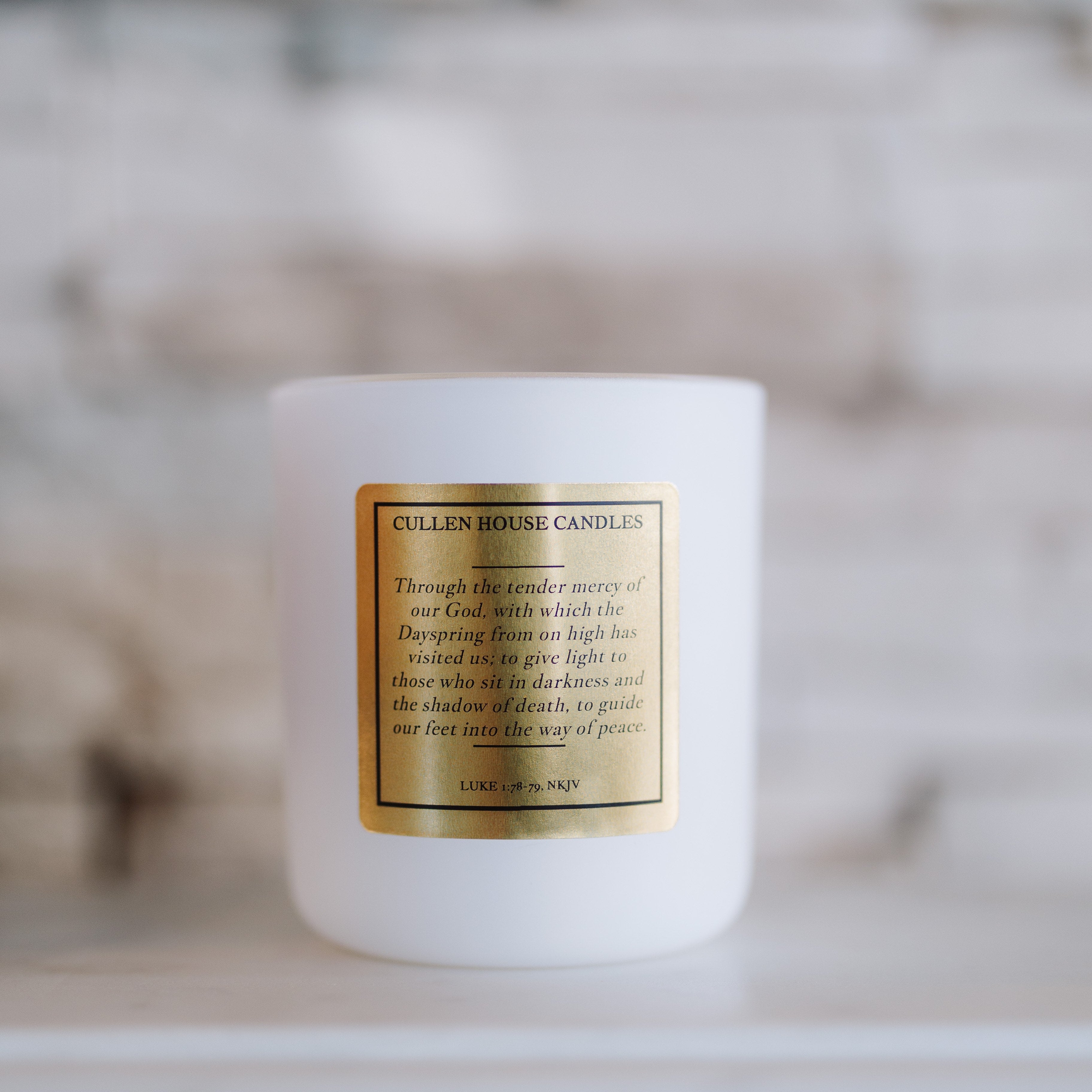 White candle with a gold label on a blurred background