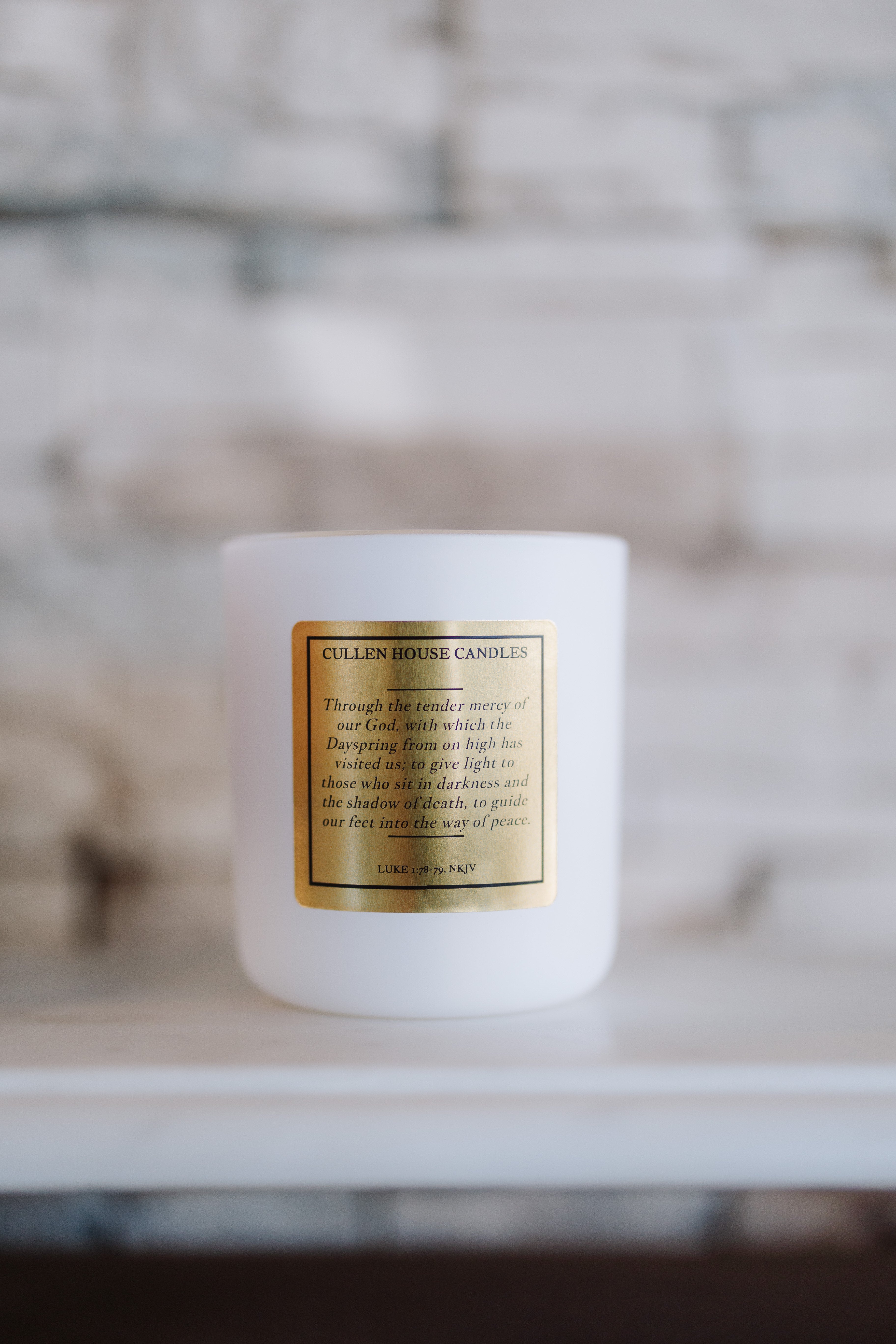 White candle with a gold label on a blurred background