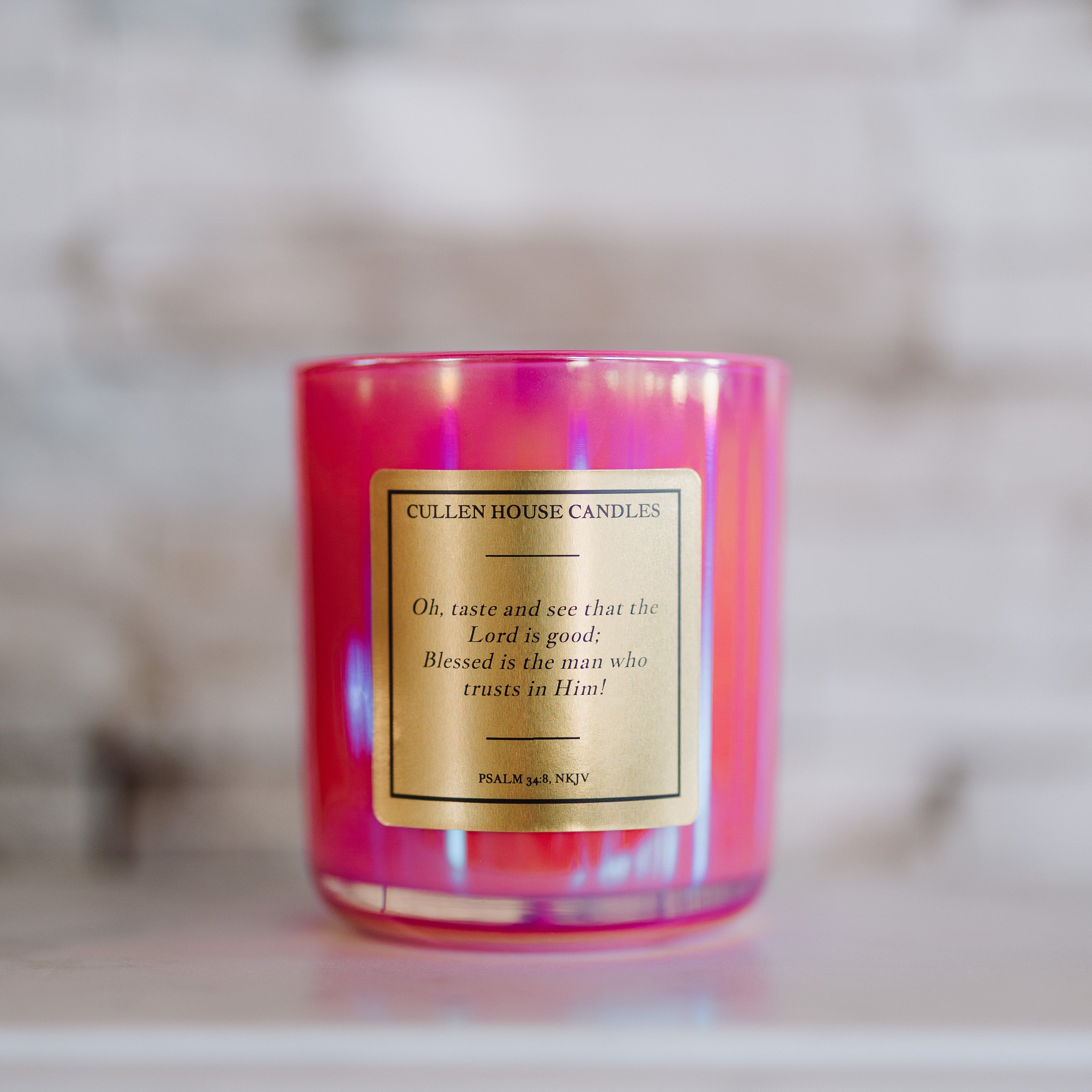 Pink candle with a label on a marble surface