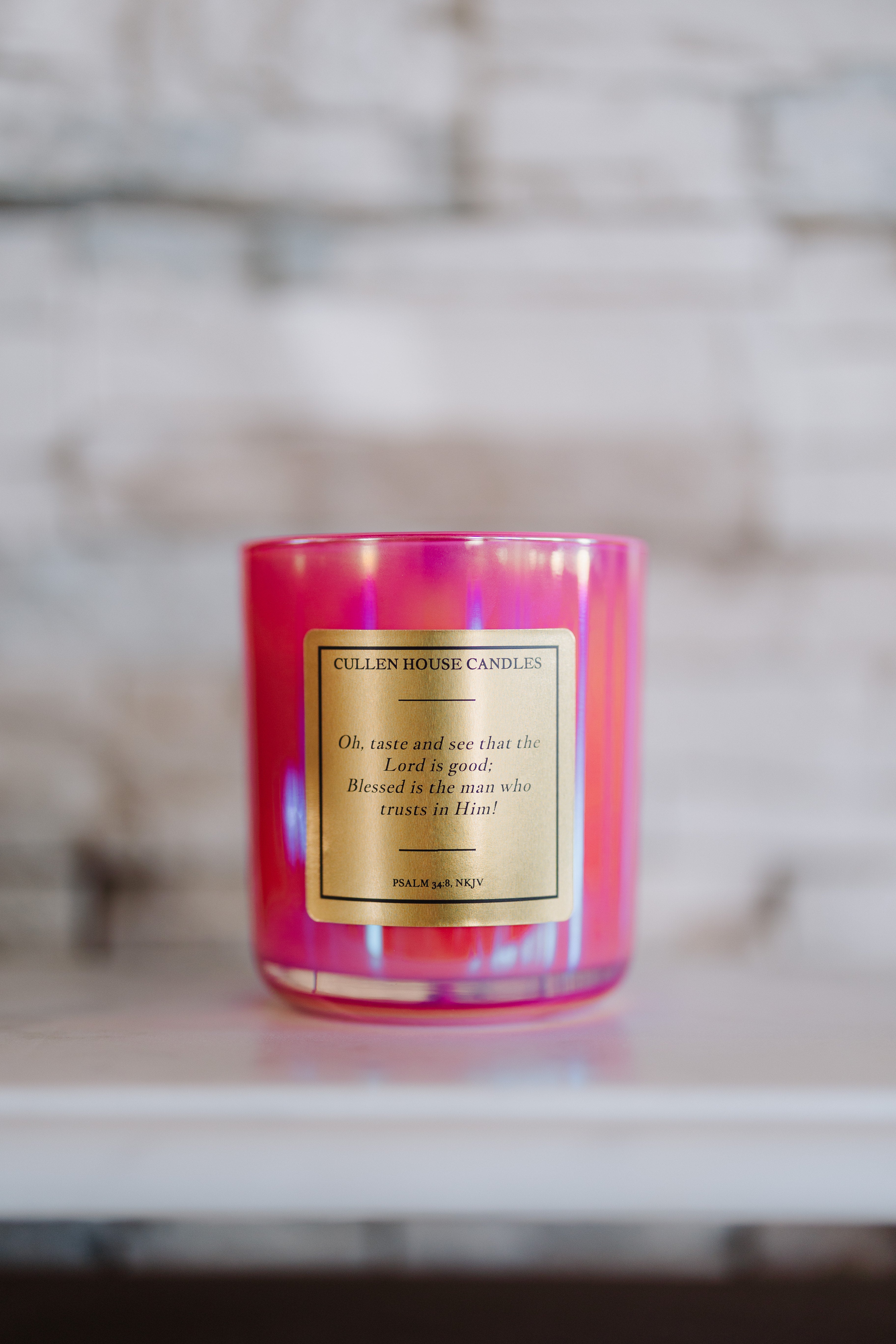 Pink candle with a label on a marble surface