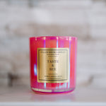 Pink candle with a gold label on a marble surface
