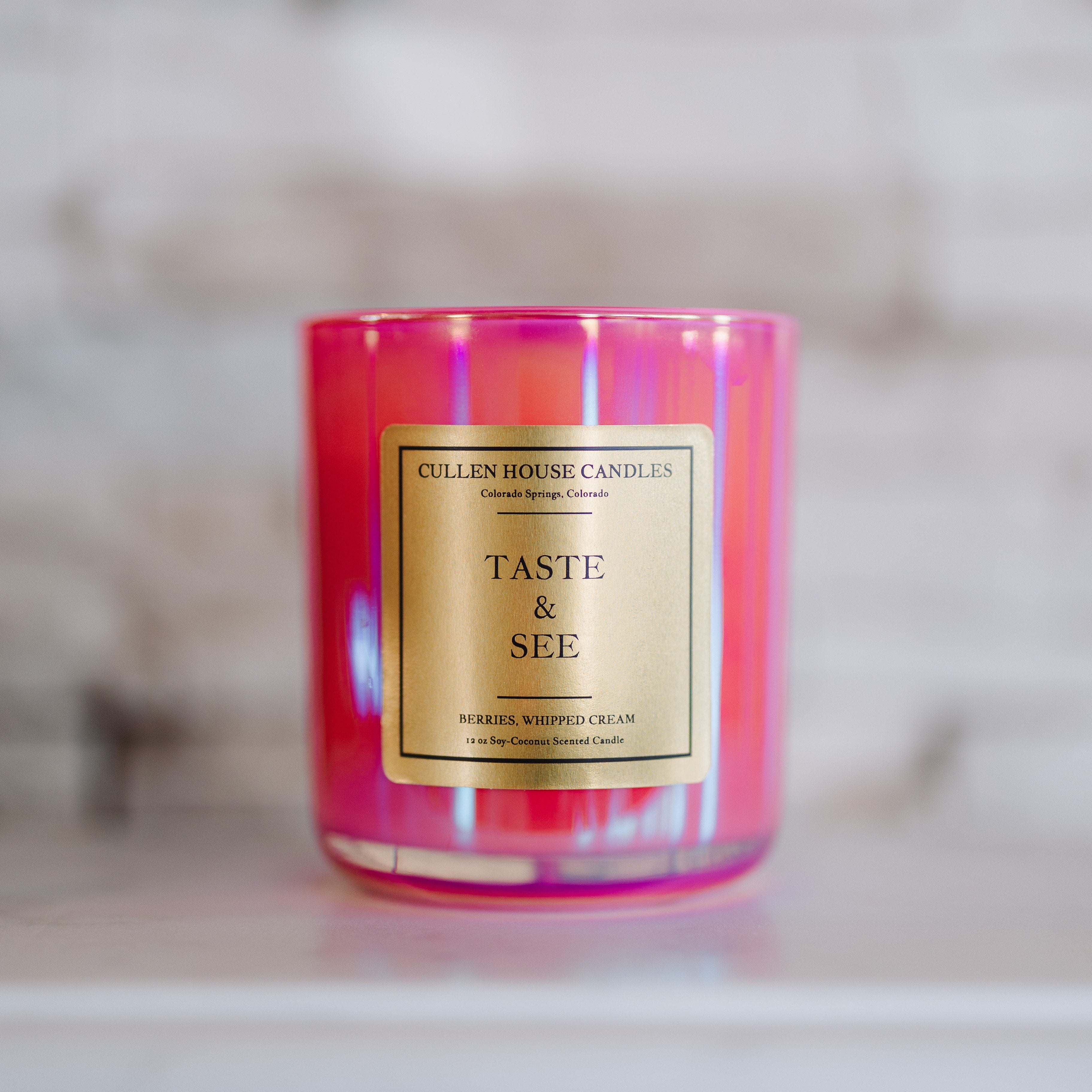 Pink candle with a gold label on a marble surface
