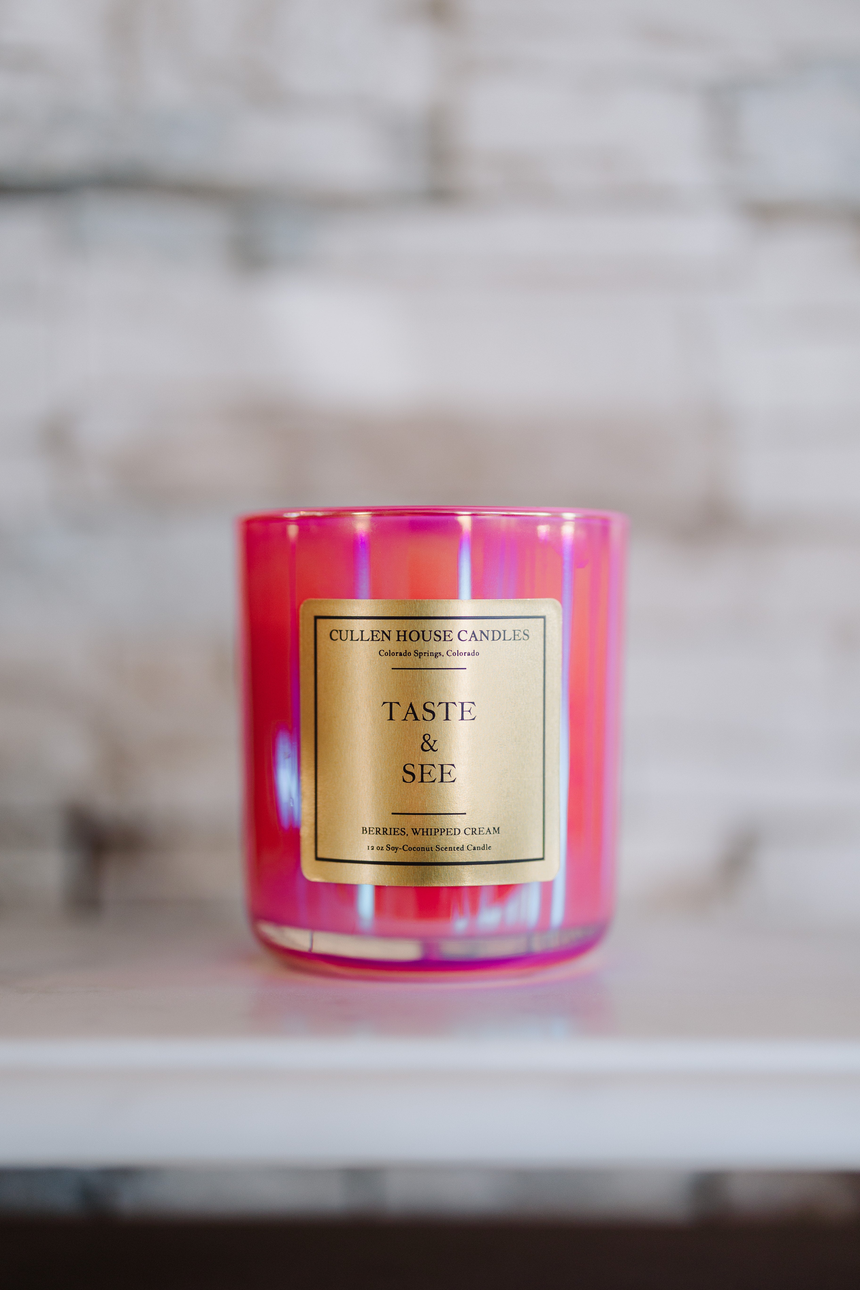 Pink candle with a gold label on a marble surface