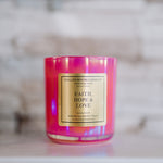 Pink candle with a gold label on a marble surface