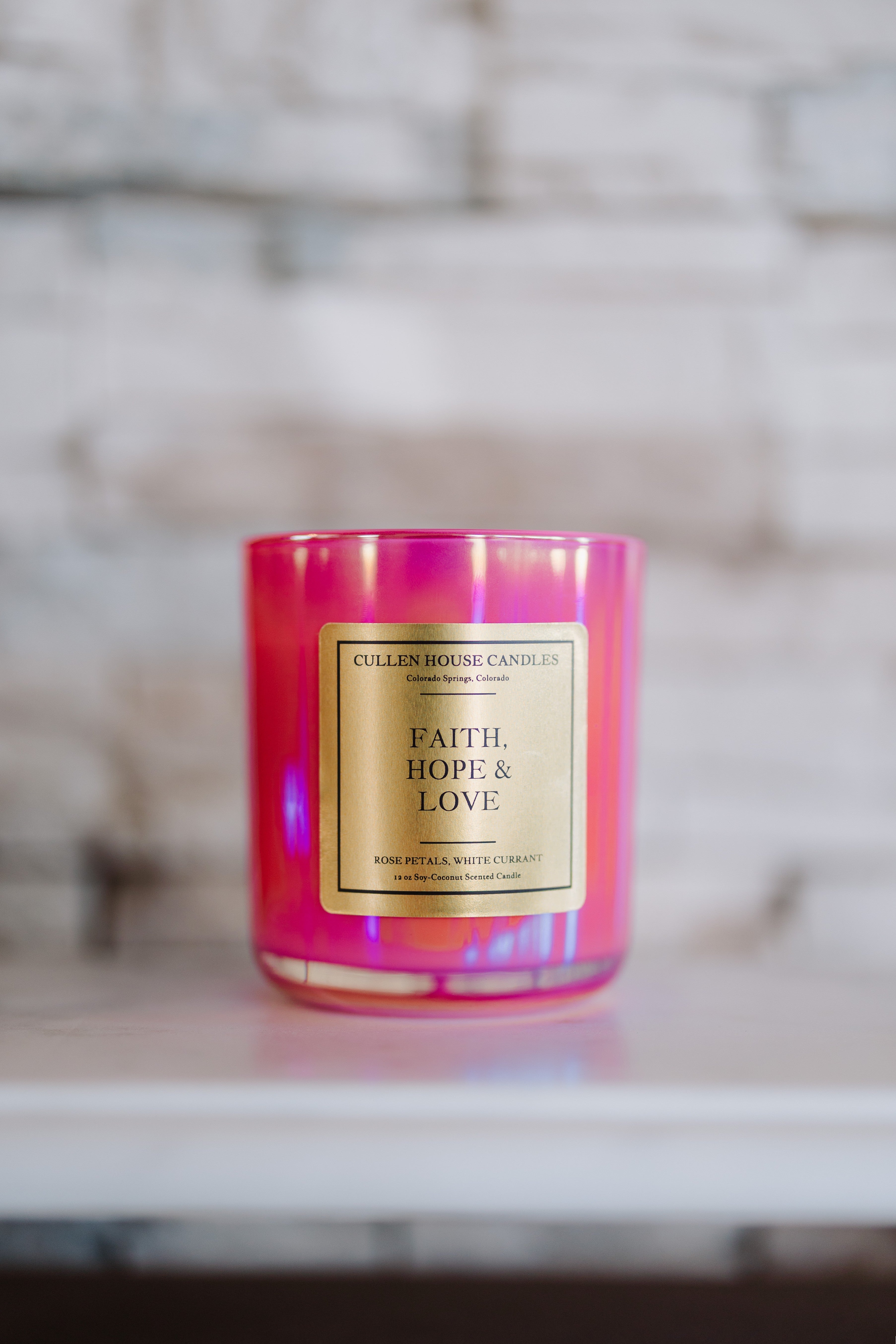 Pink candle with a gold label on a marble surface