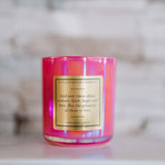 Pink candle with a gold label on a marble surface
