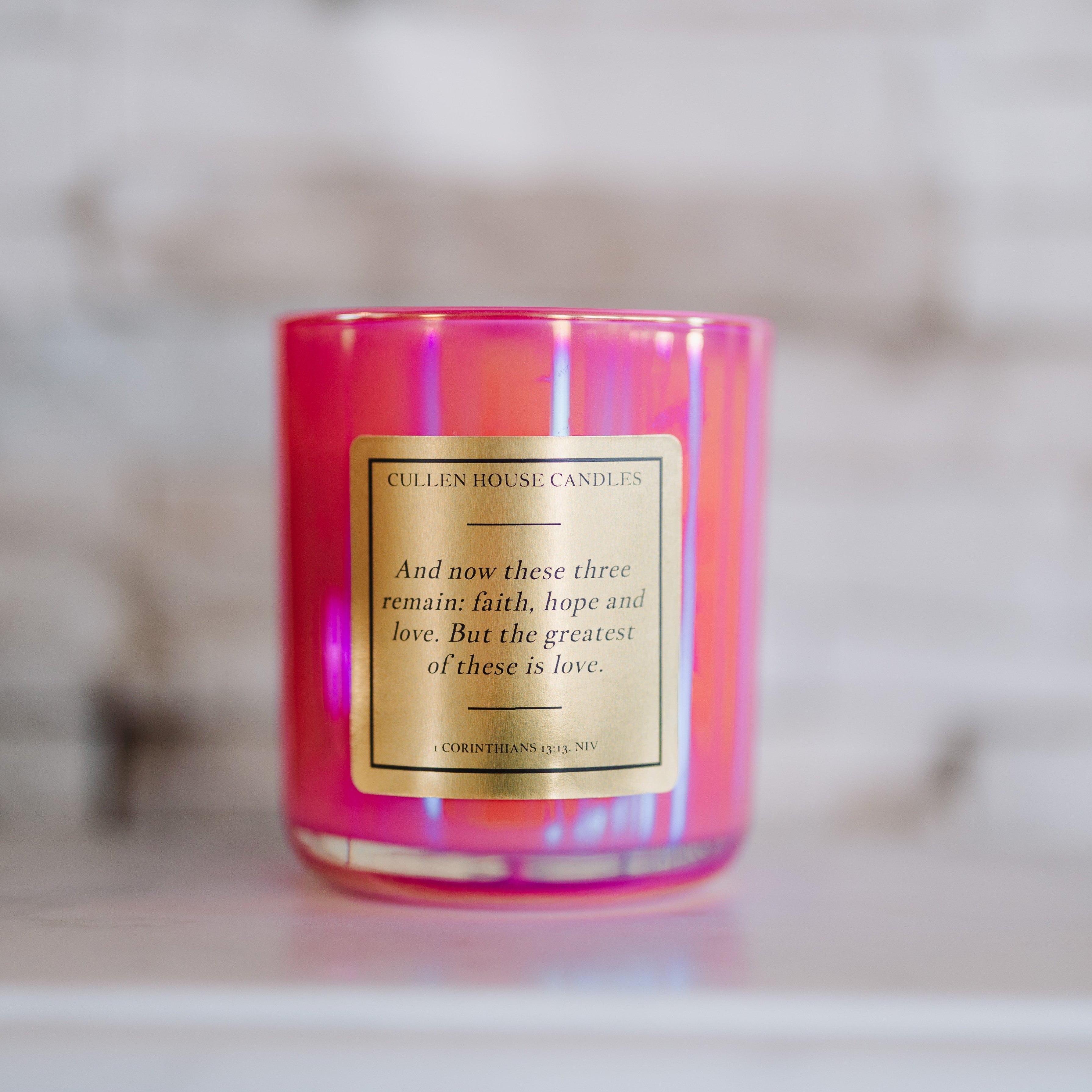 Pink candle with a gold label on a marble surface