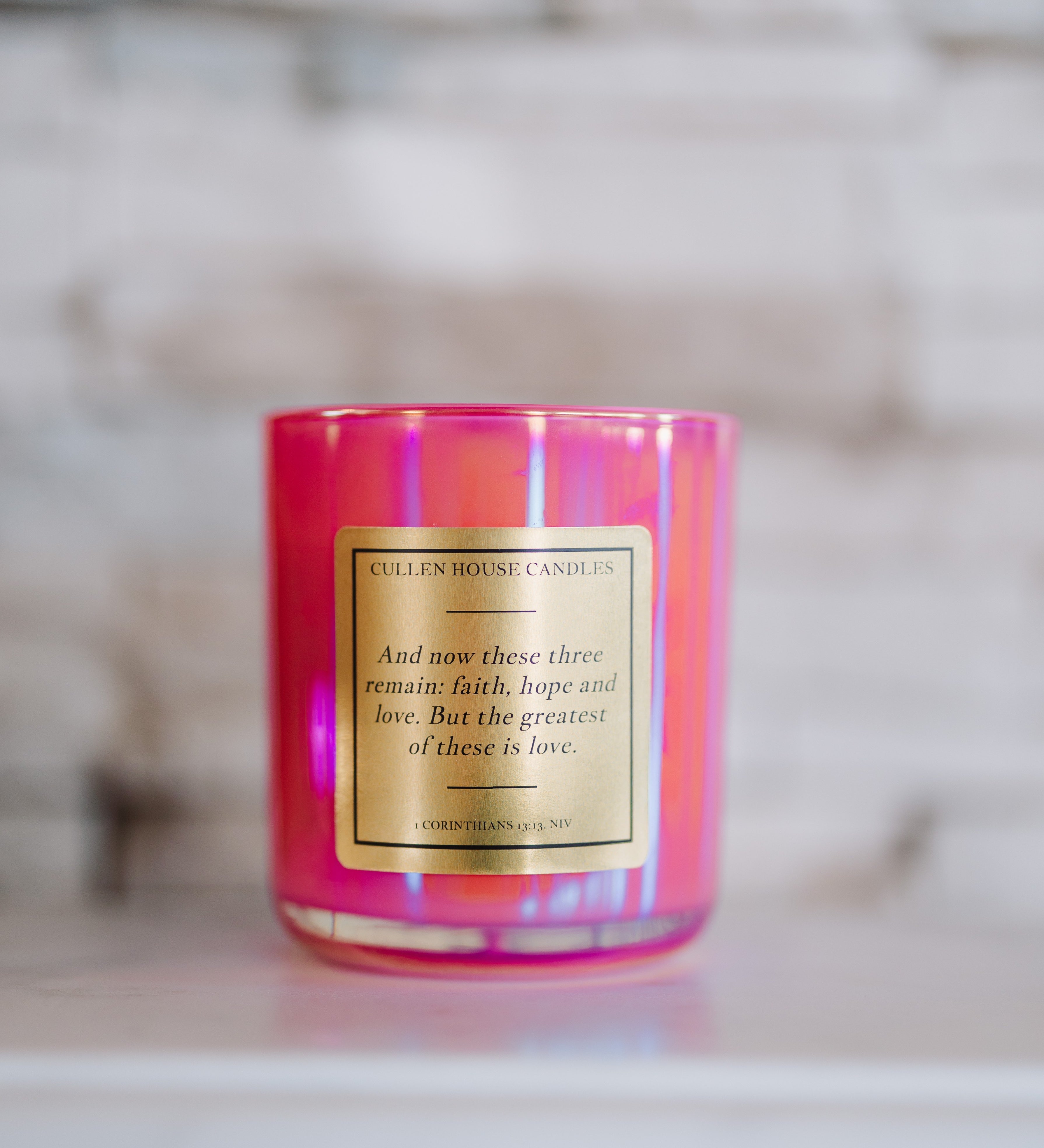 Pink candle with a gold label on a marble surface