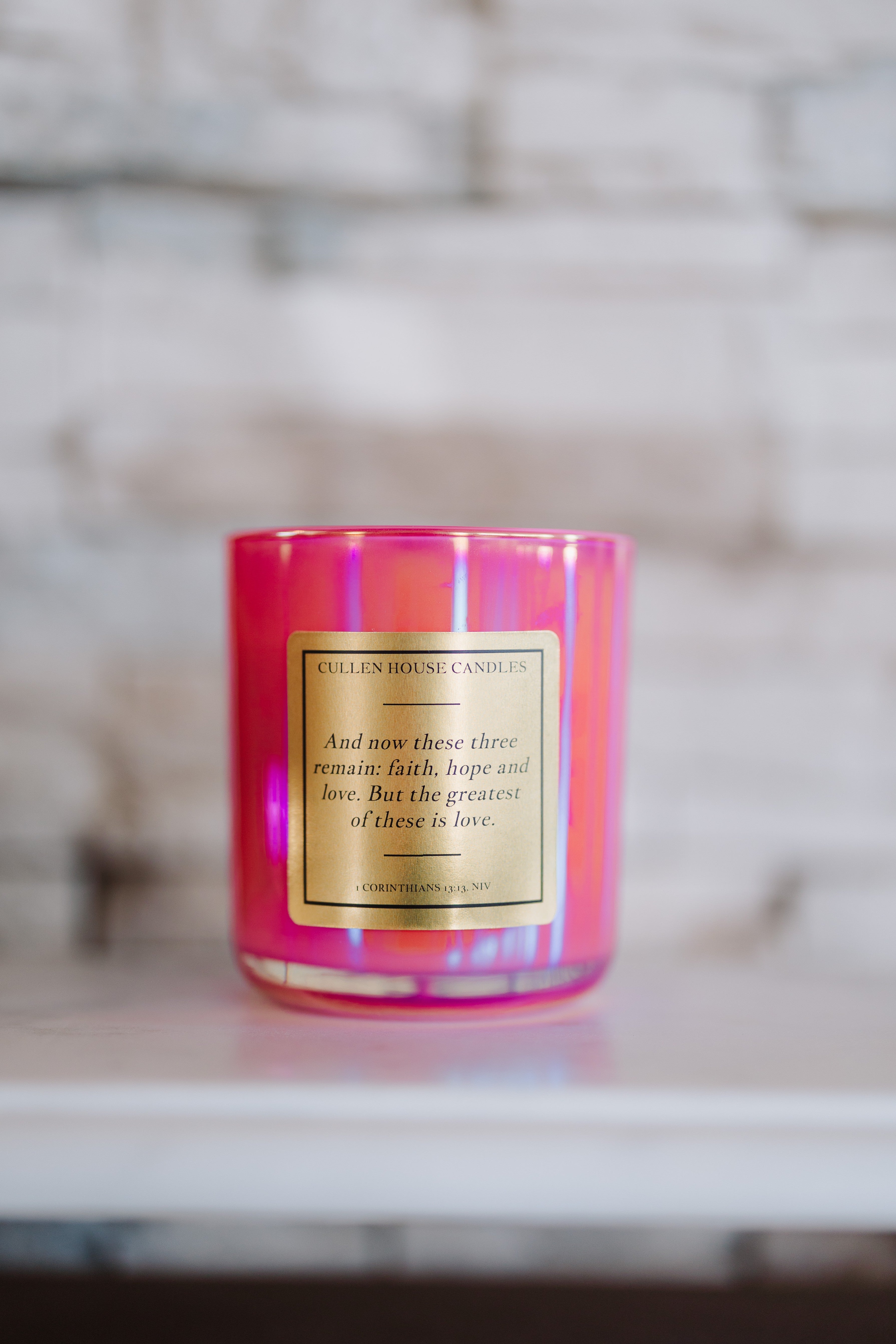 Pink candle with a gold label on a marble surface