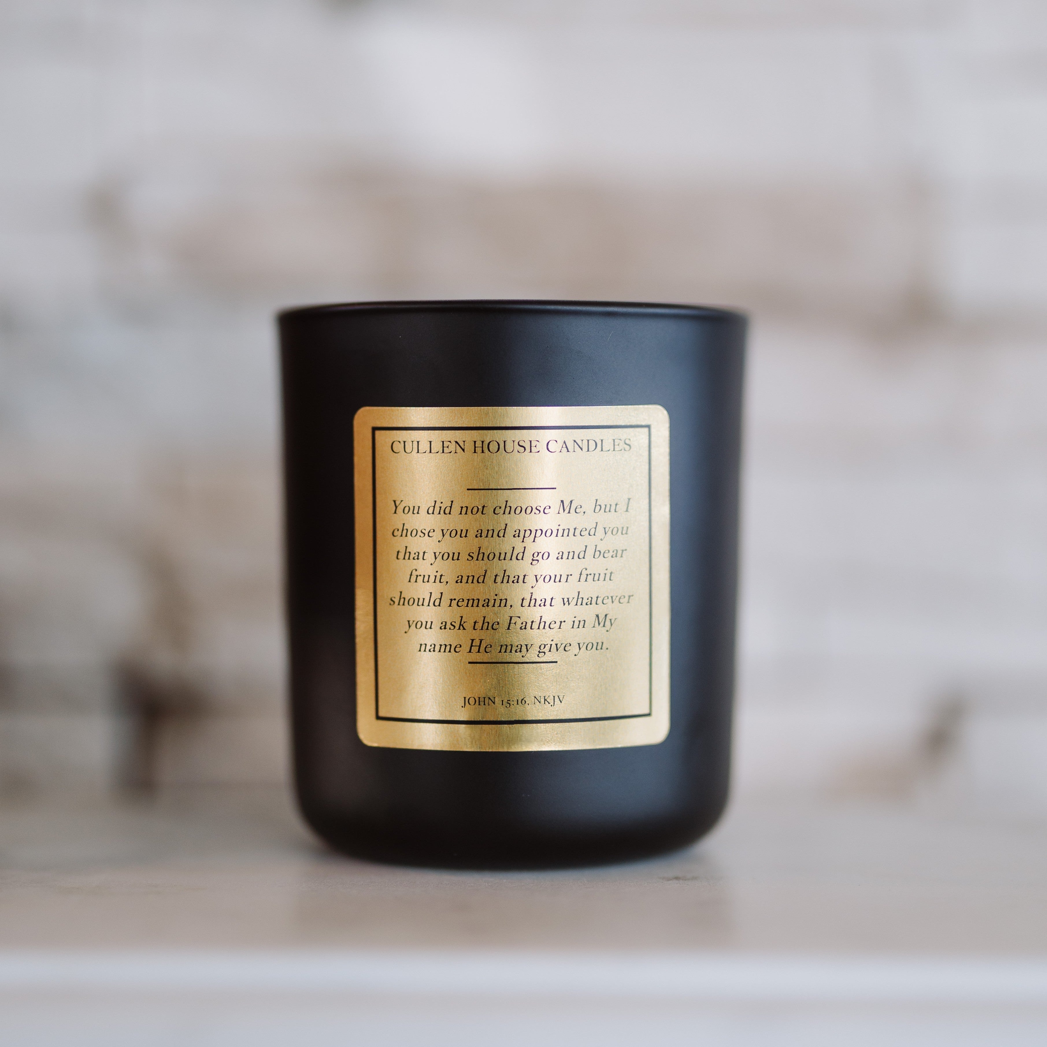Black candle with a gold label on a wooden surface with a blurred background