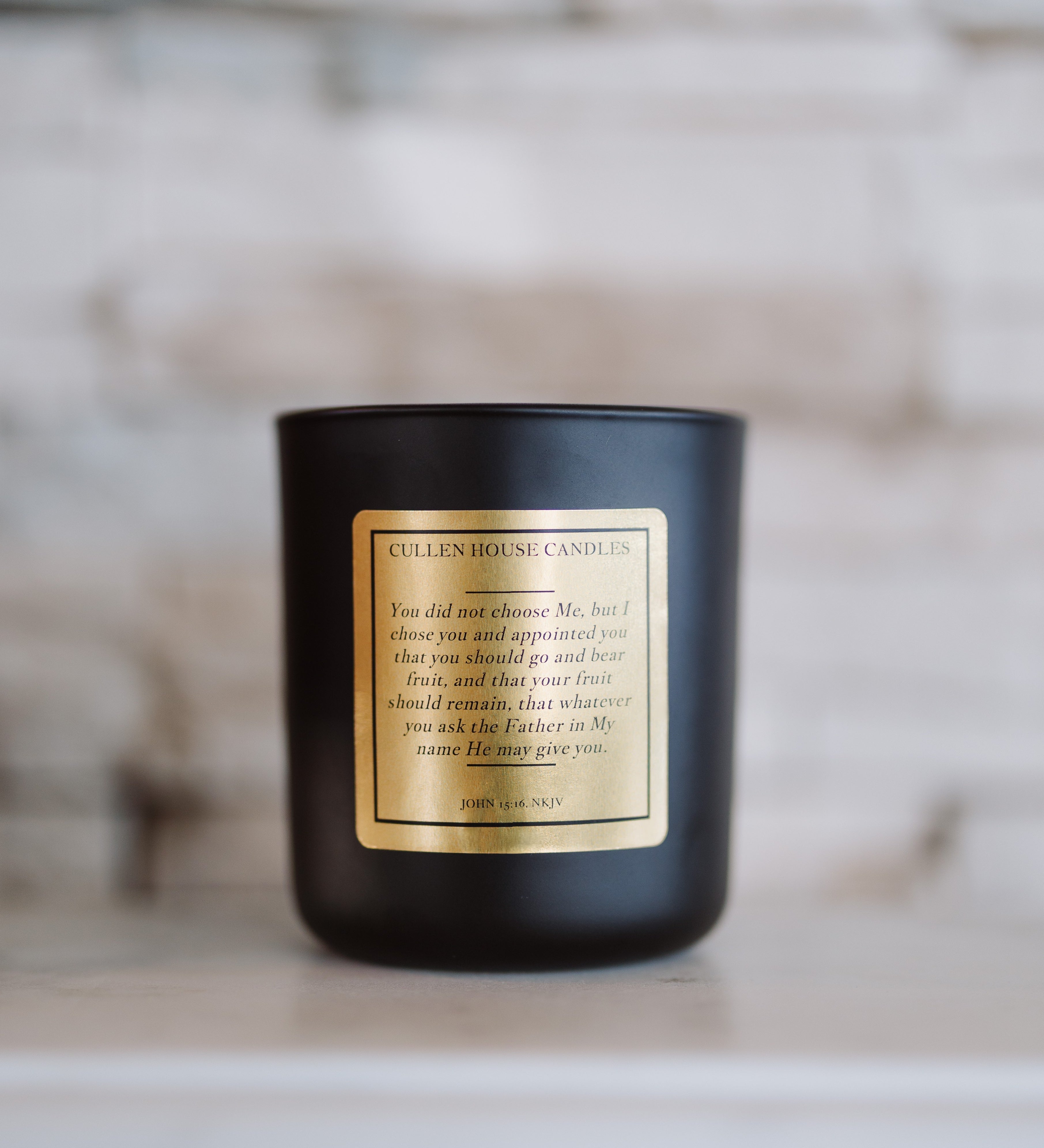 Black candle with a gold label on a wooden surface with a blurred background