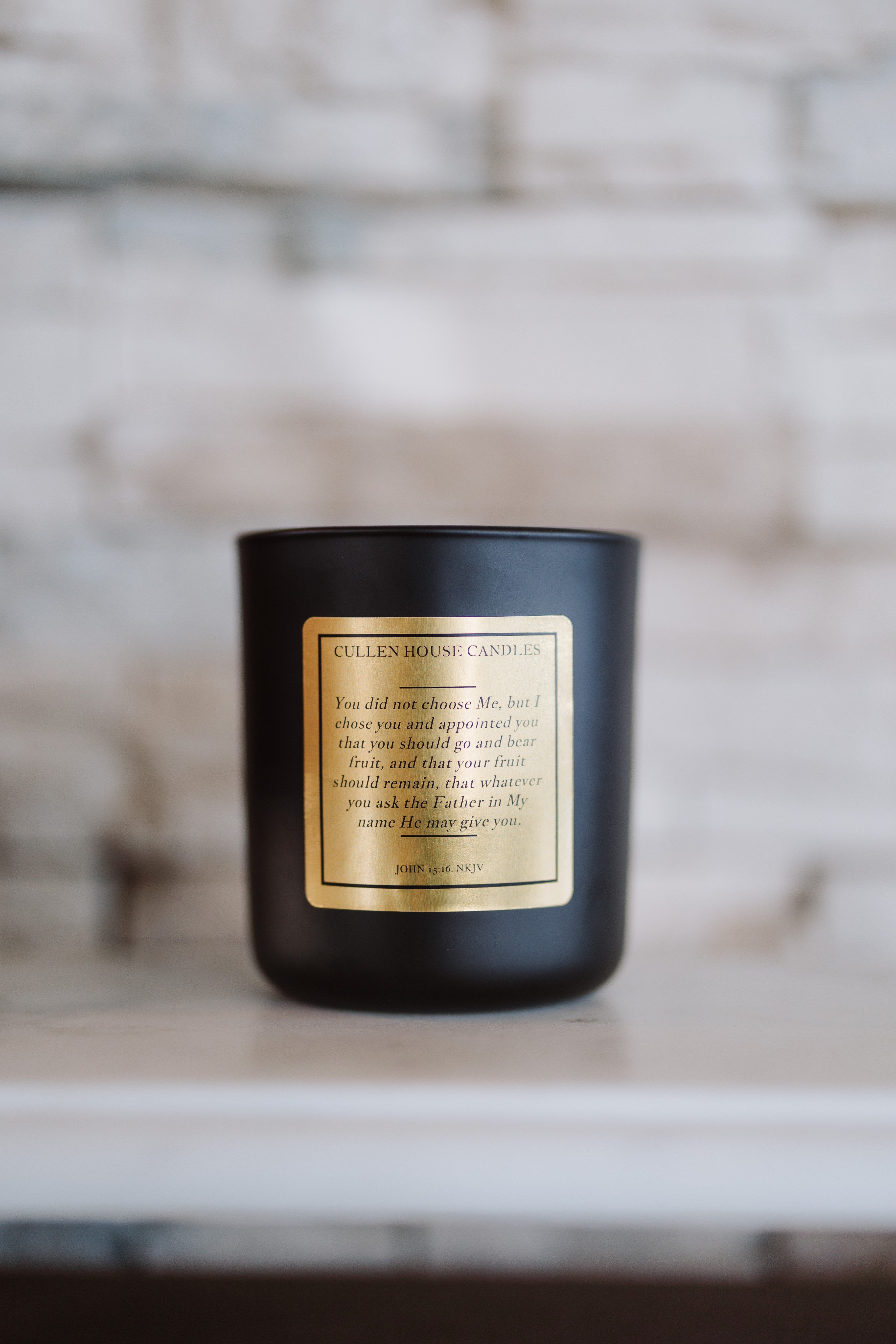 Black candle with a gold label on a wooden surface with a blurred background