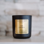 Black candle with a gold label on a wooden surface