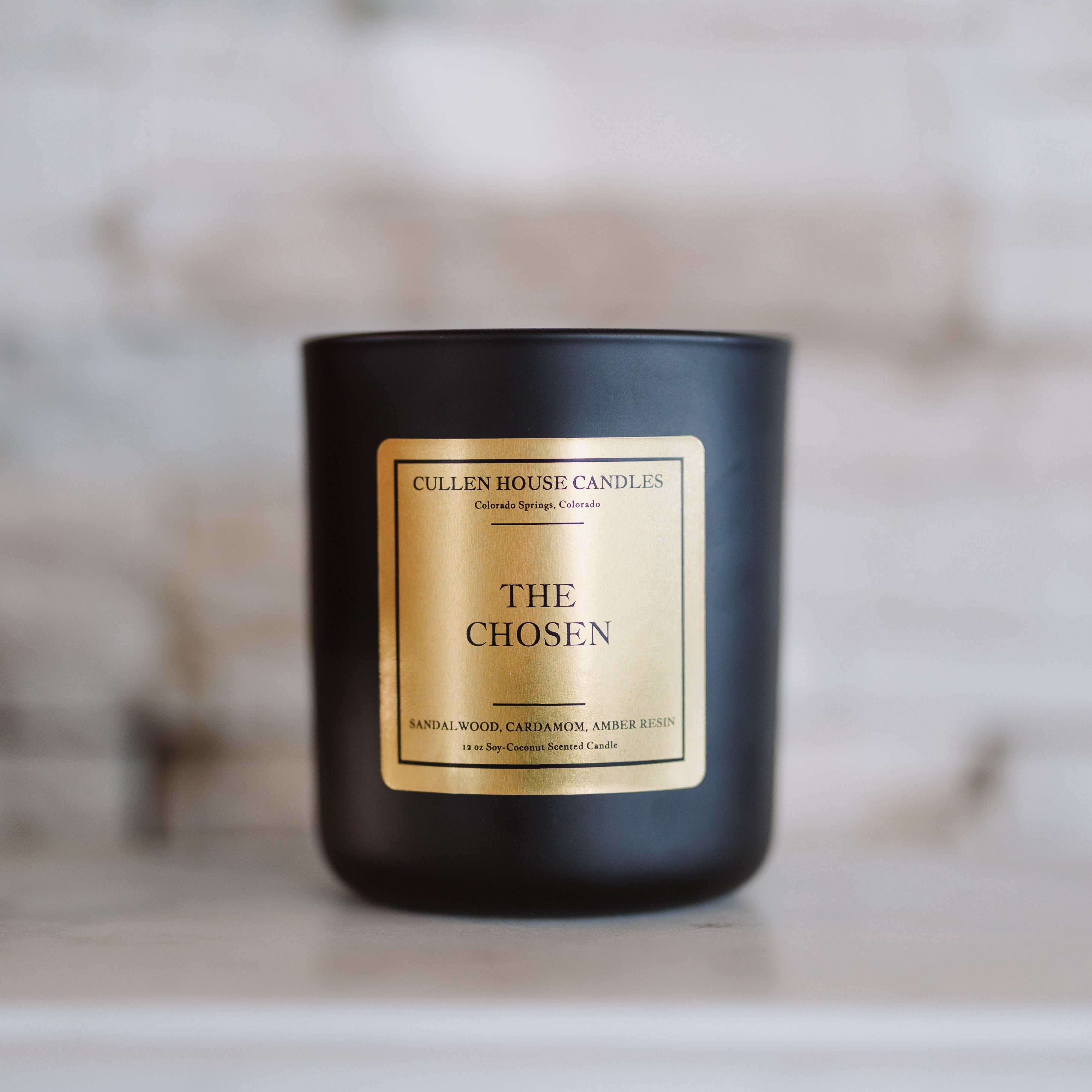 Black candle with a gold label on a wooden surface
