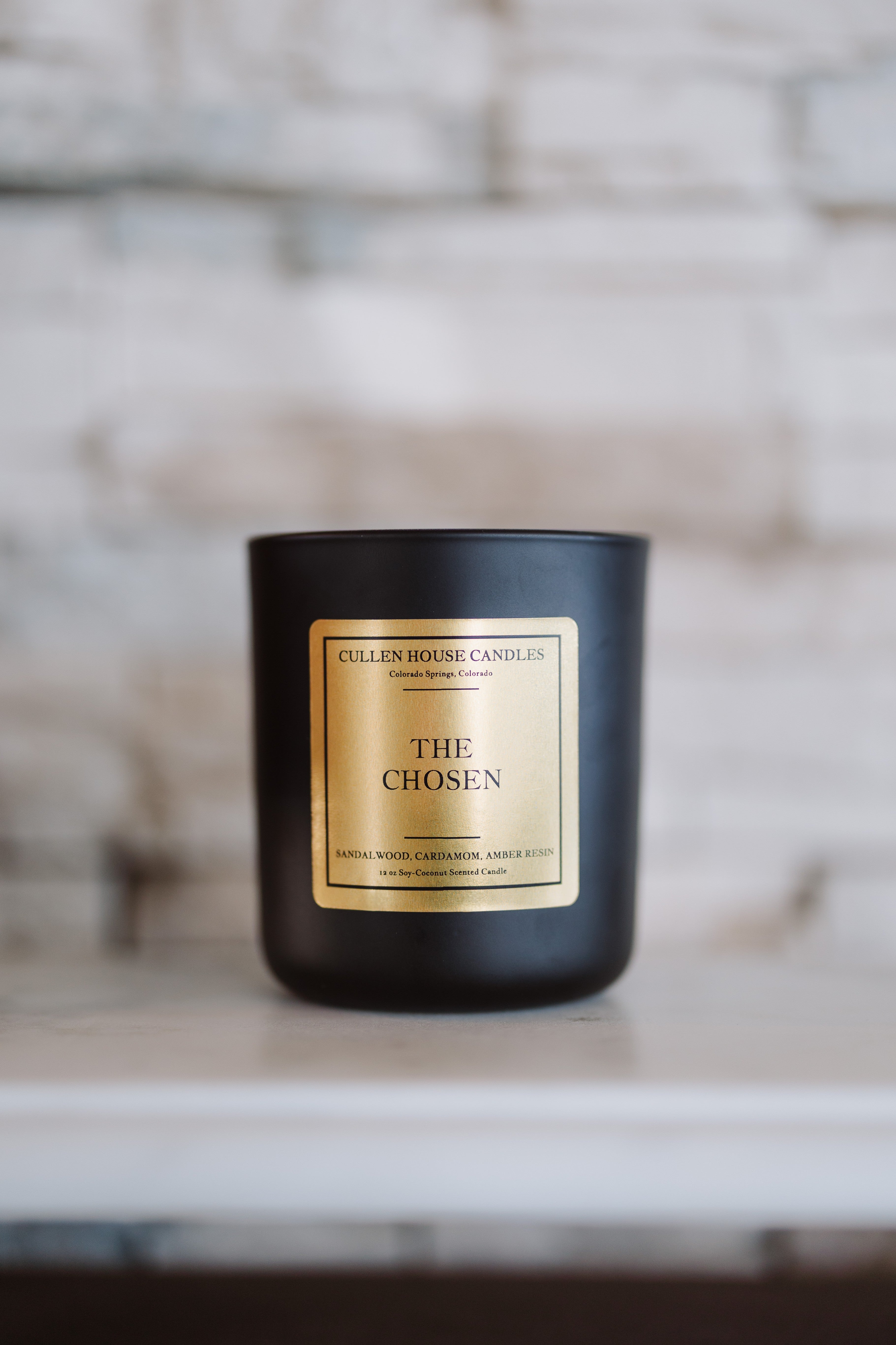 Black candle with a gold label on a wooden surface