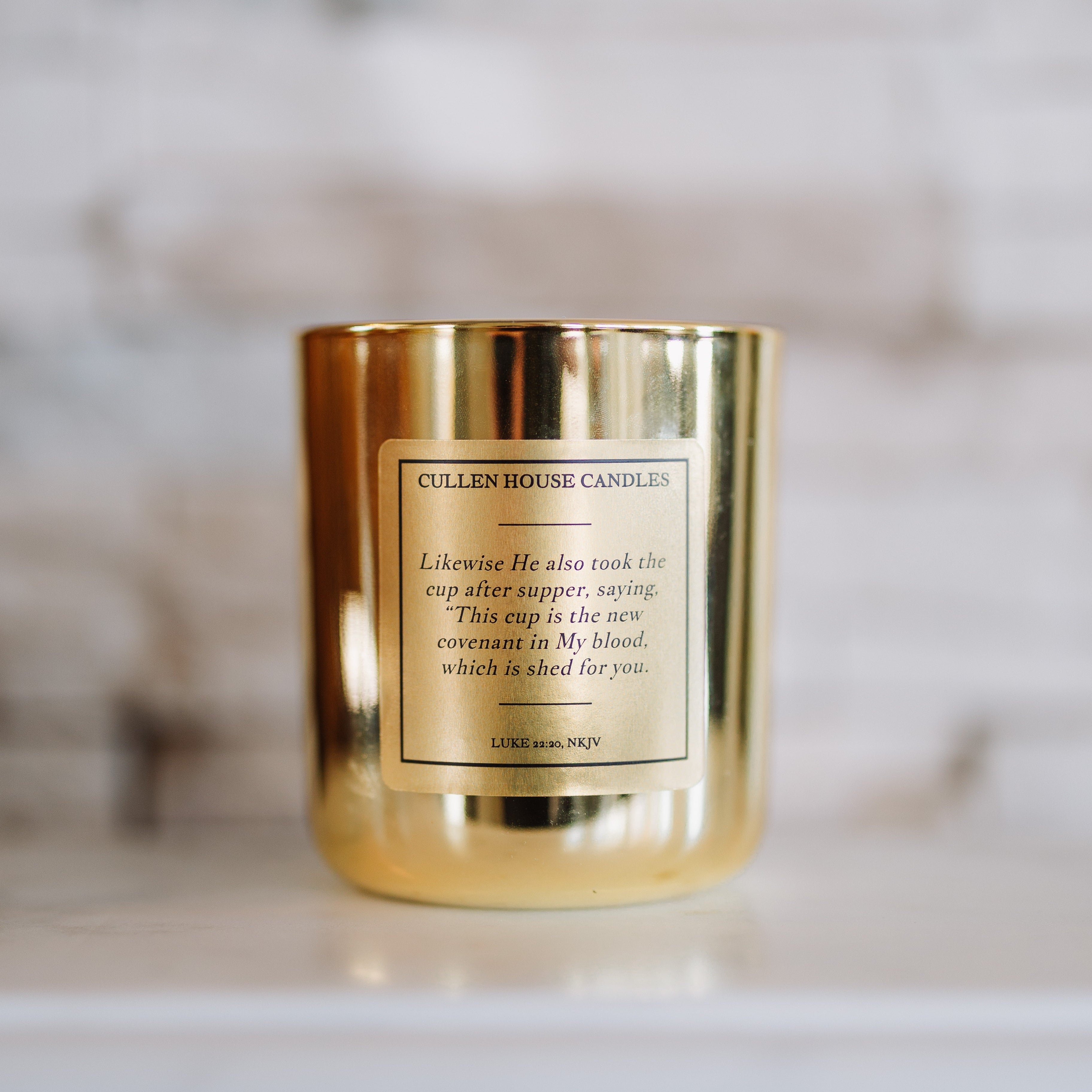 Gold candle with a label on a marble surface