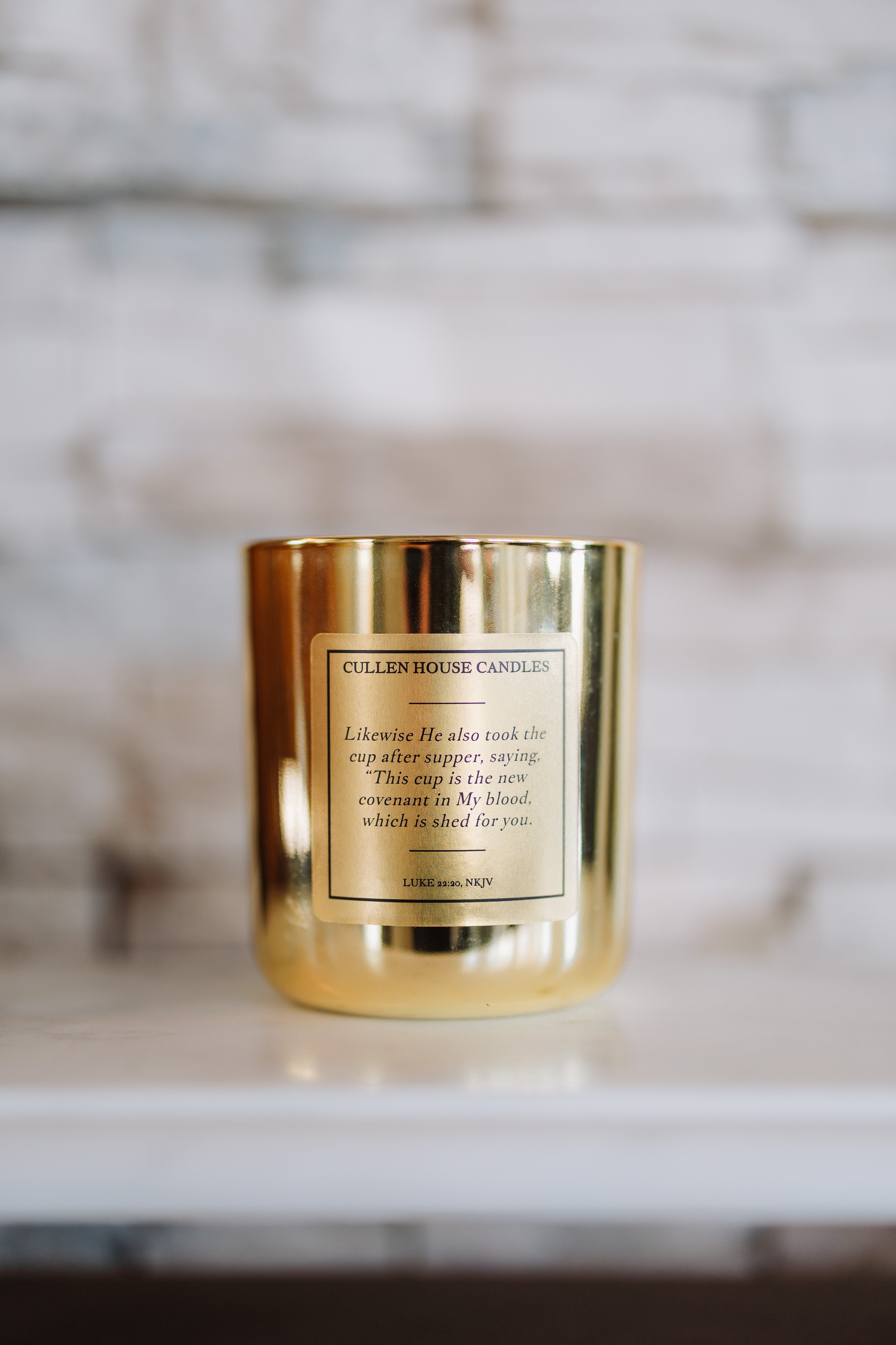 Gold candle with a label on a marble surface