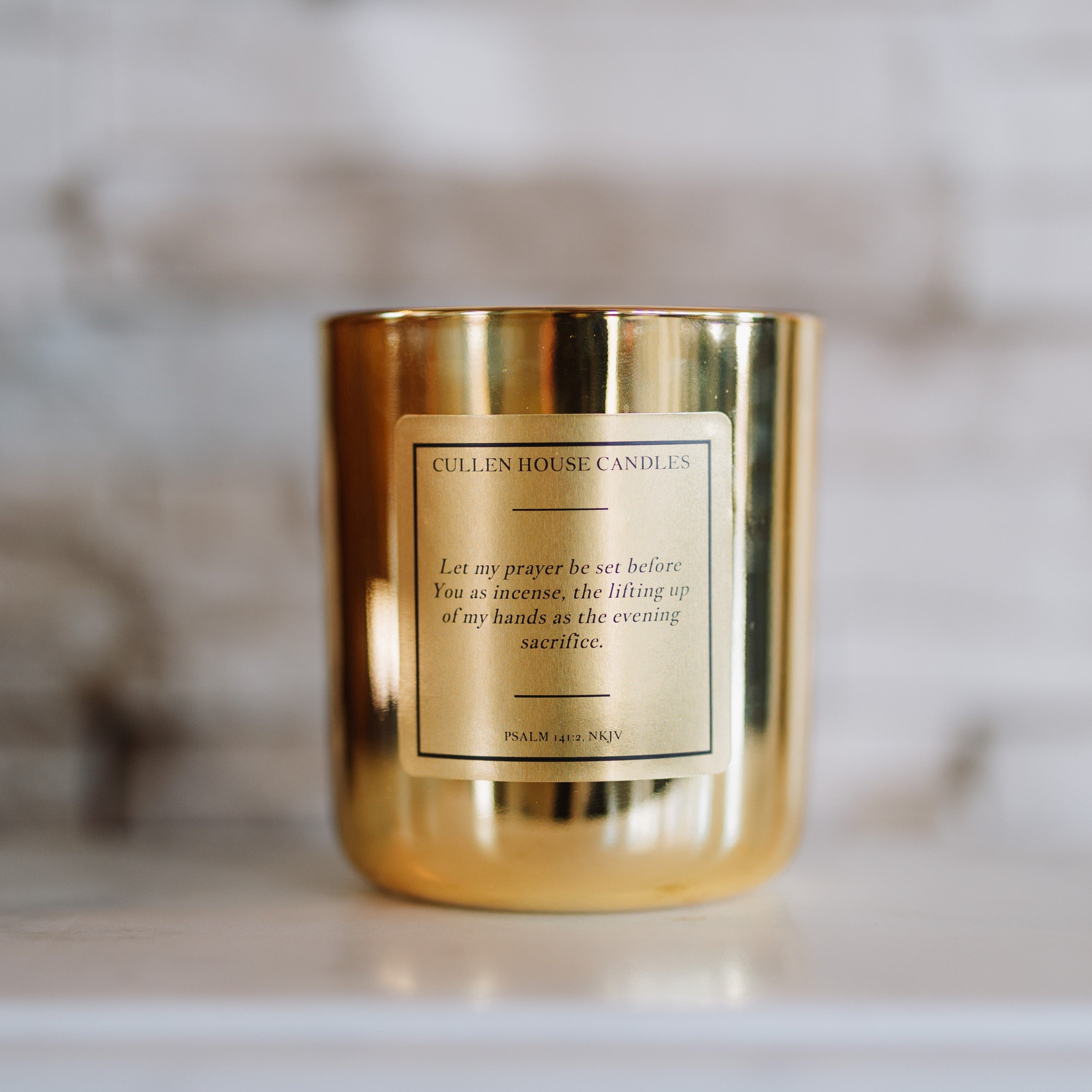 Gold candle with a label on a marble surface