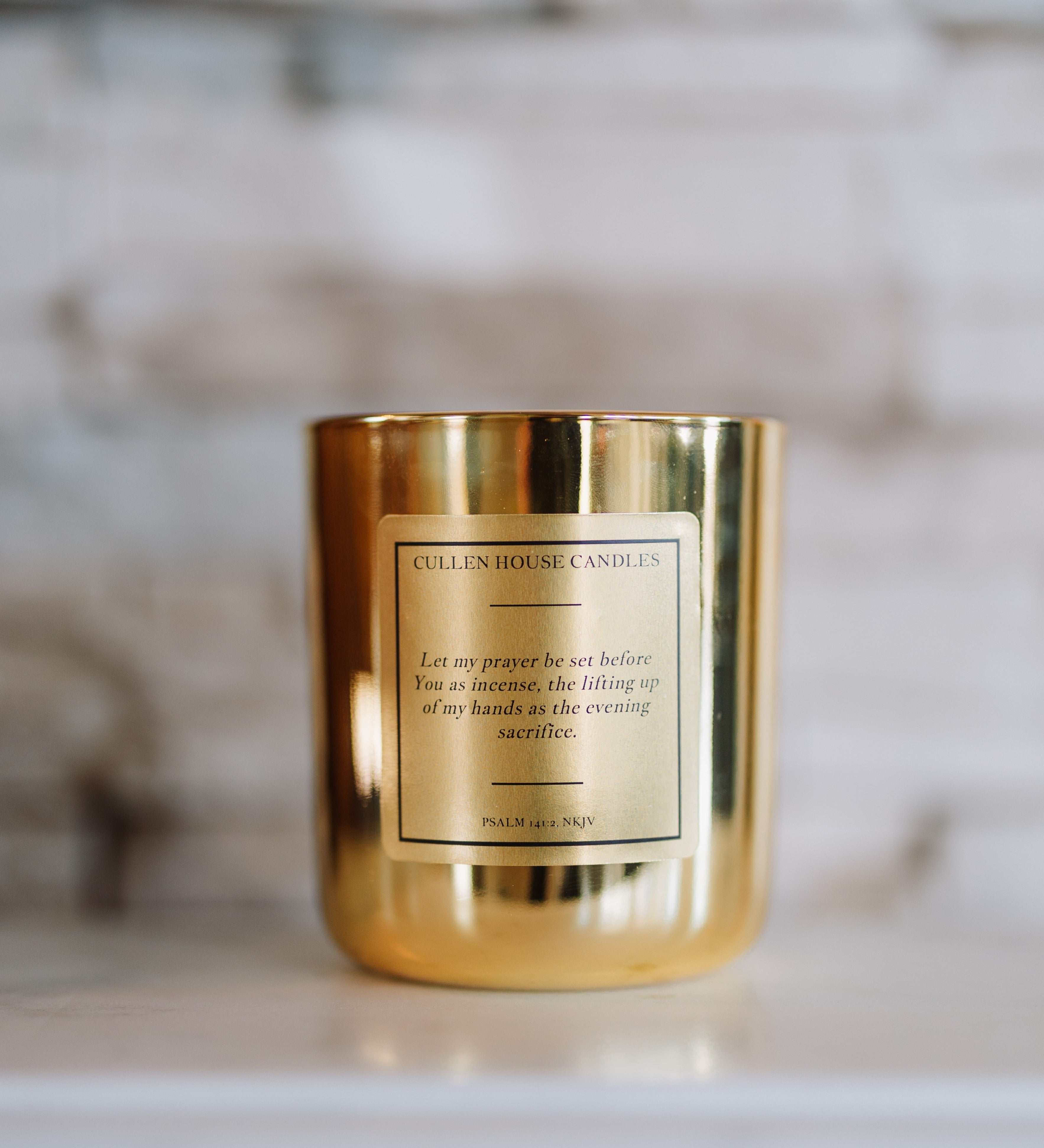Gold candle with a label on a marble surface
