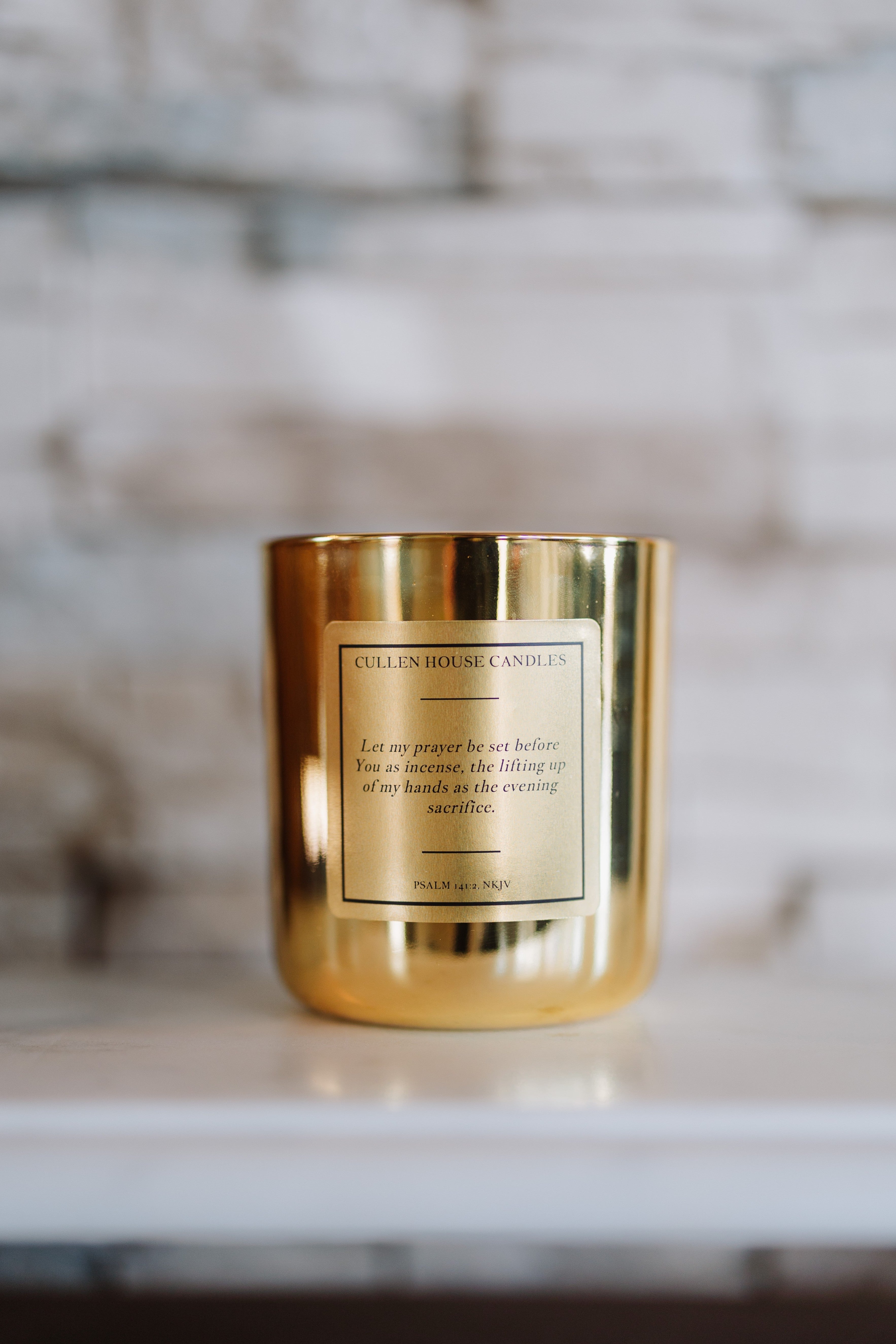 Gold candle with a label on a marble surface