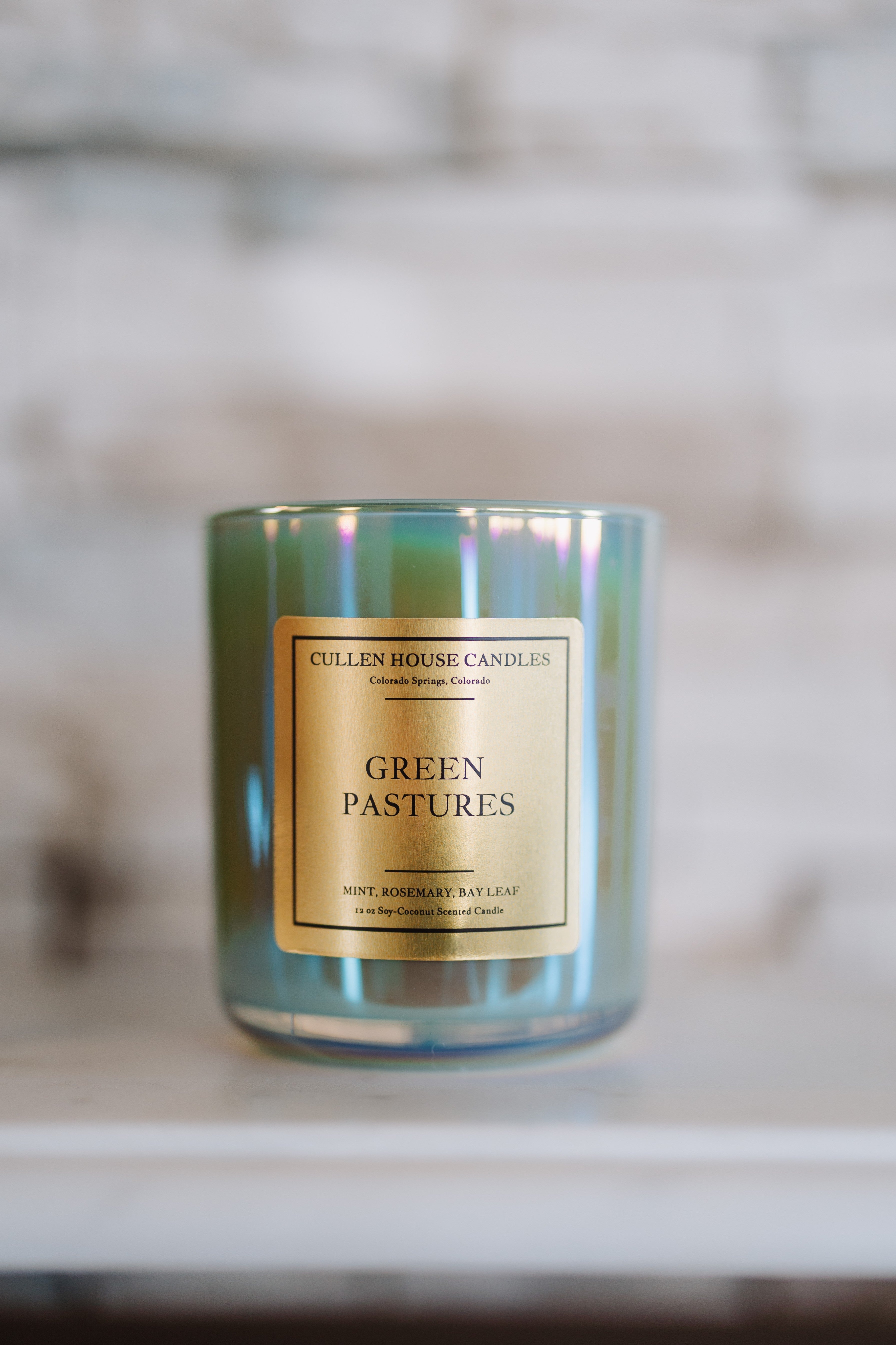 Candle with 'Green Pastures' label on a blurred background
