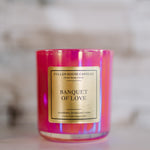 Candle with 'Banquet of Love' label on a reflective surface