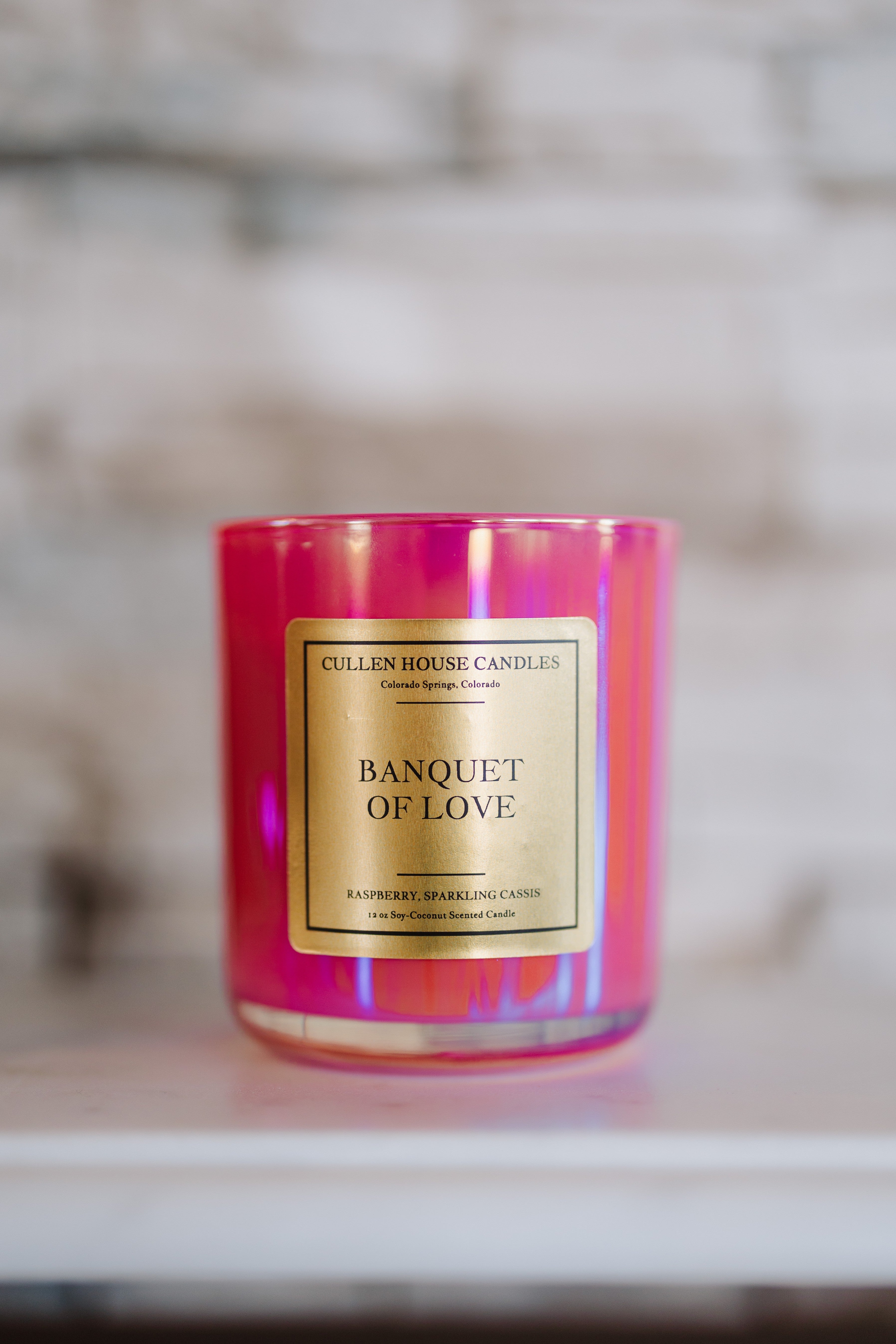Candle with 'Banquet of Love' label on a reflective surface