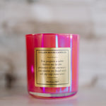 Pink candle with a gold label on a neutral background