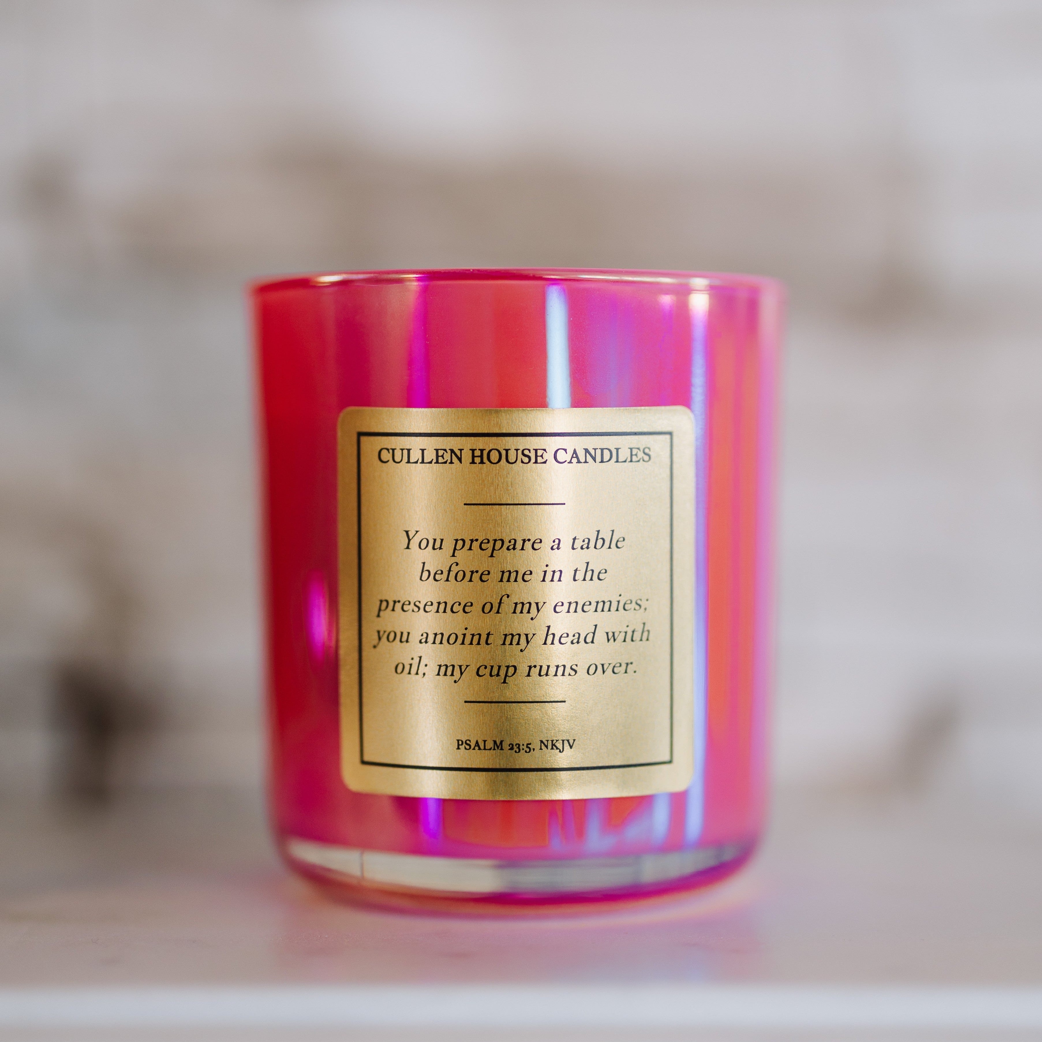 Pink candle with a gold label on a neutral background