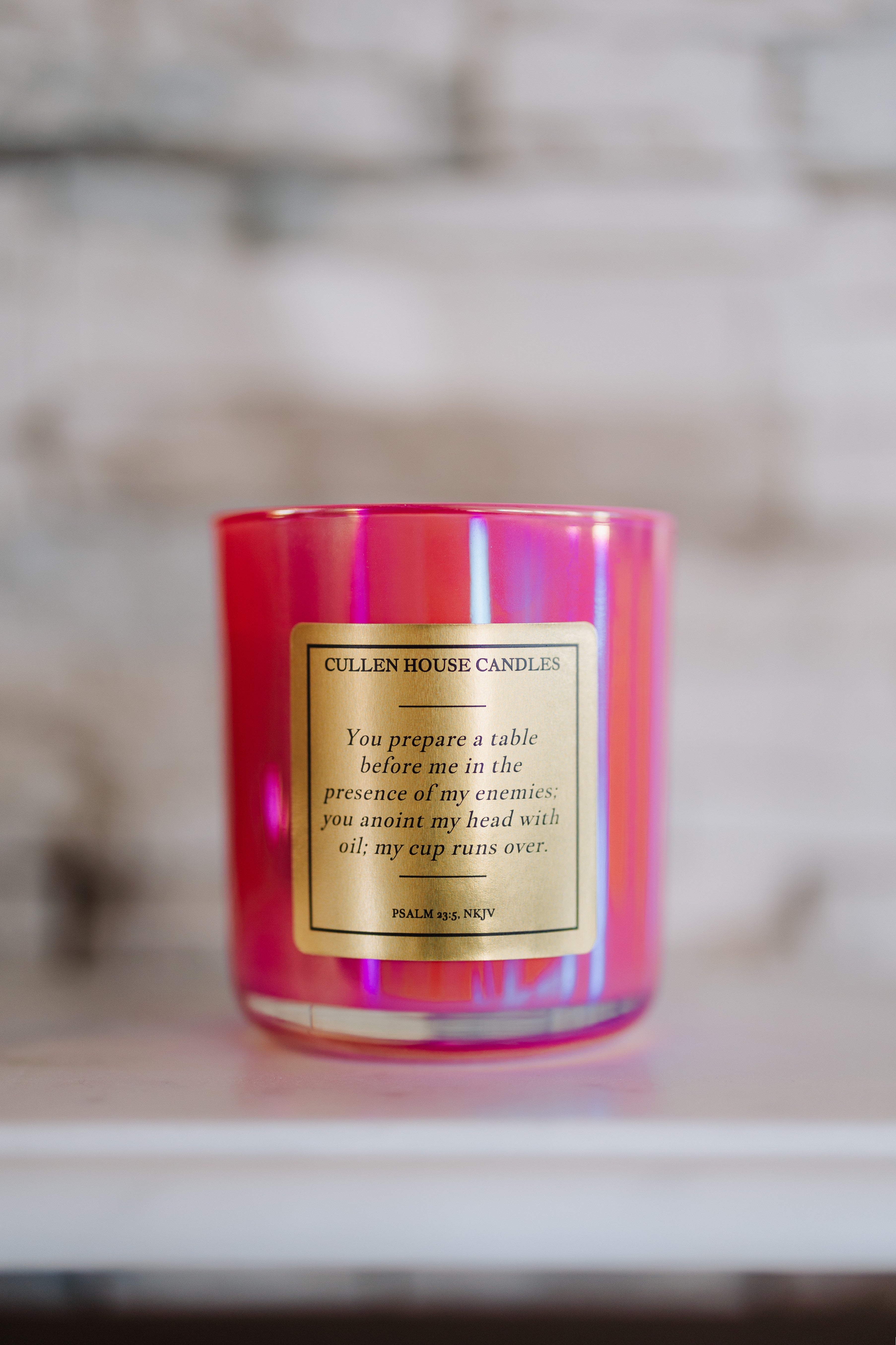 Pink candle with a gold label on a neutral background