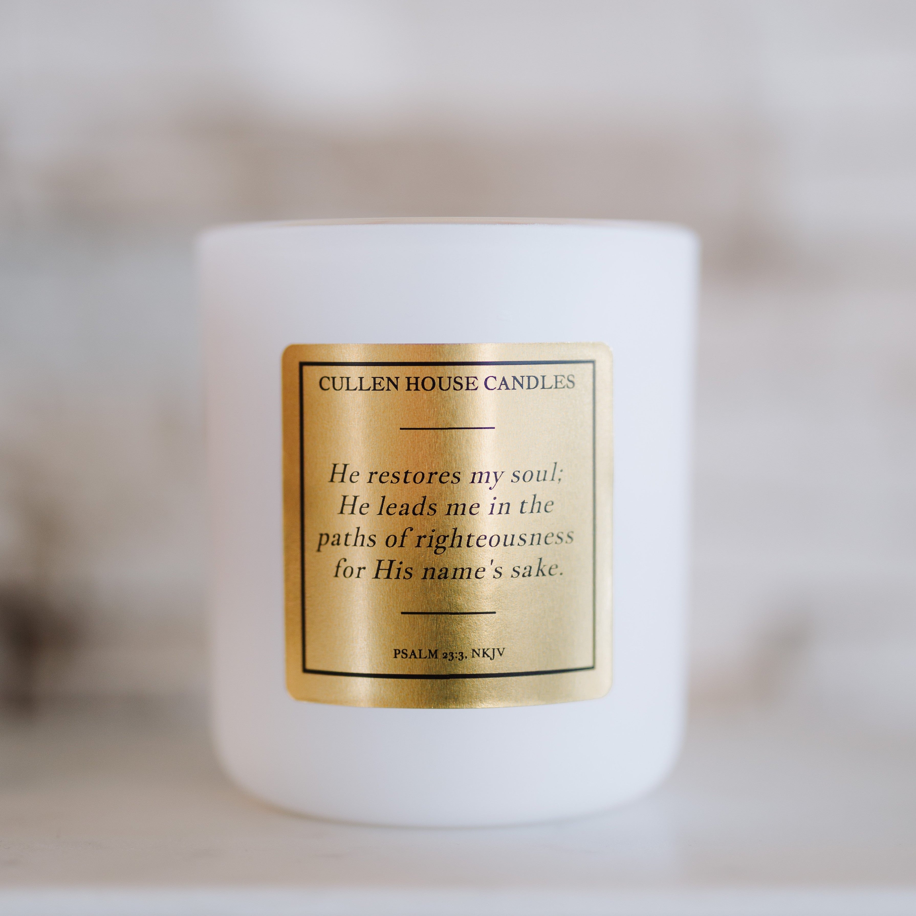 White candle with a gold label on a blurred background