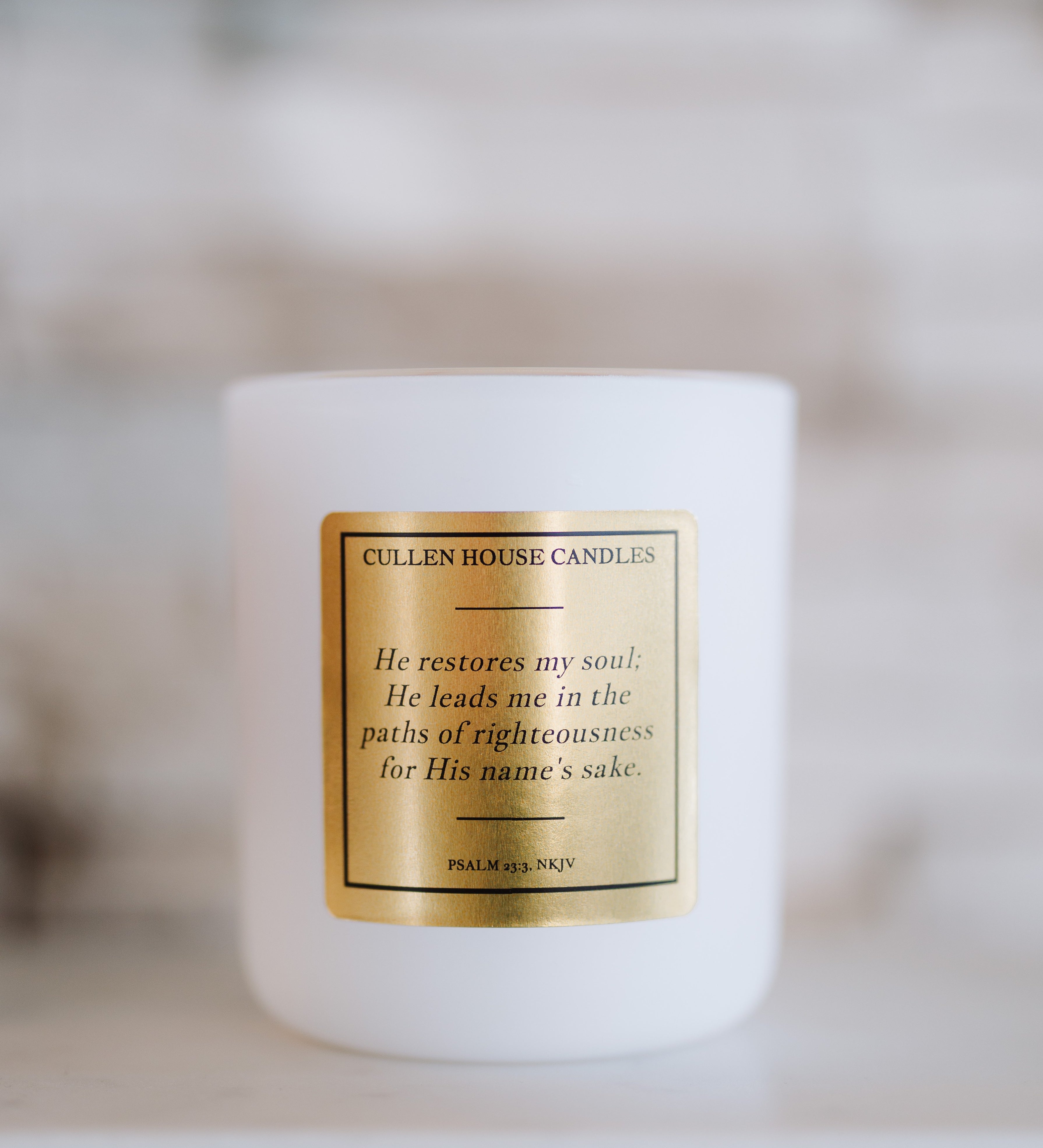 White candle with a gold label on a blurred background