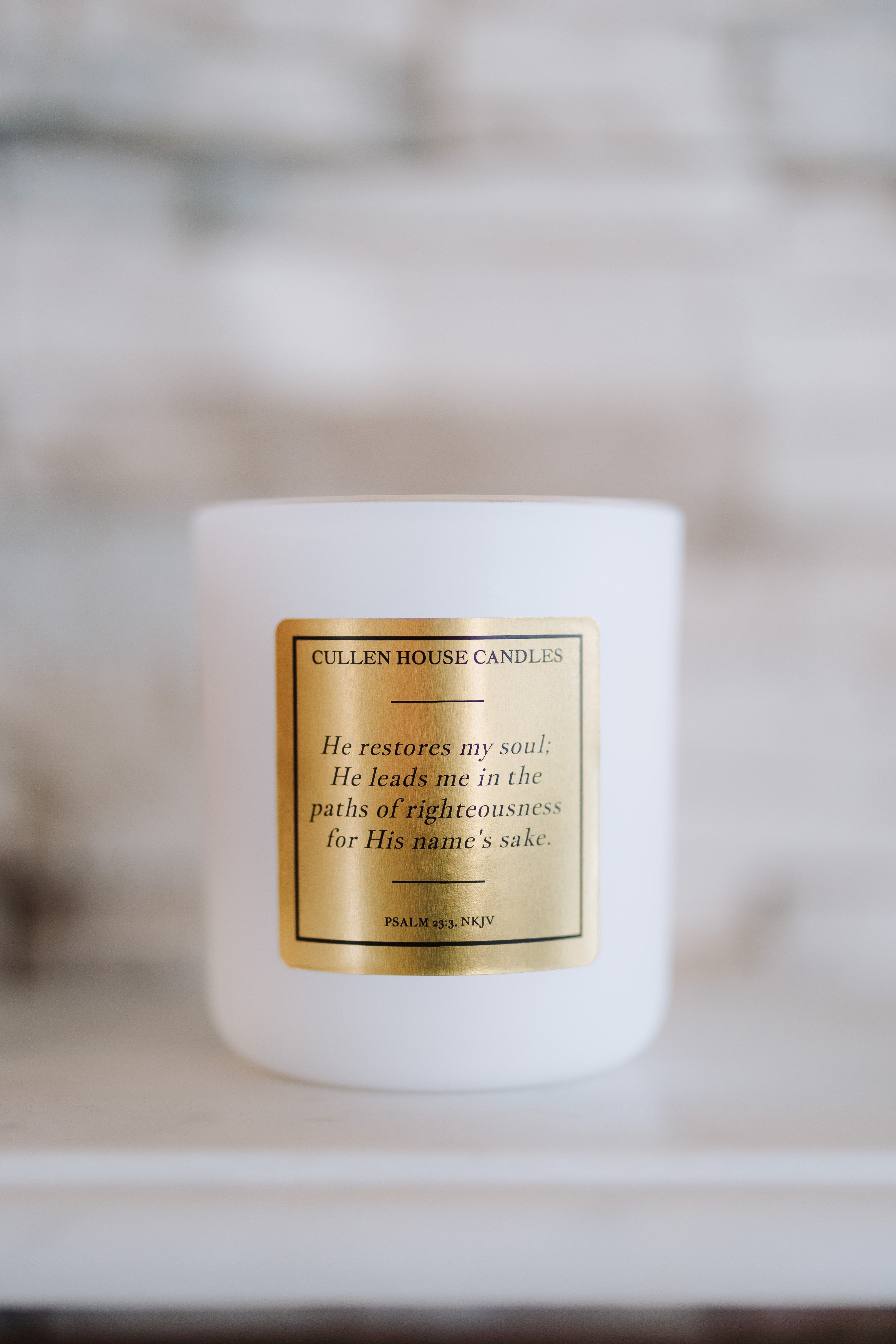 White candle with a gold label on a blurred background