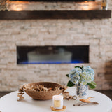 Living room with a white coffee table, decorative items, and a stone fireplace.