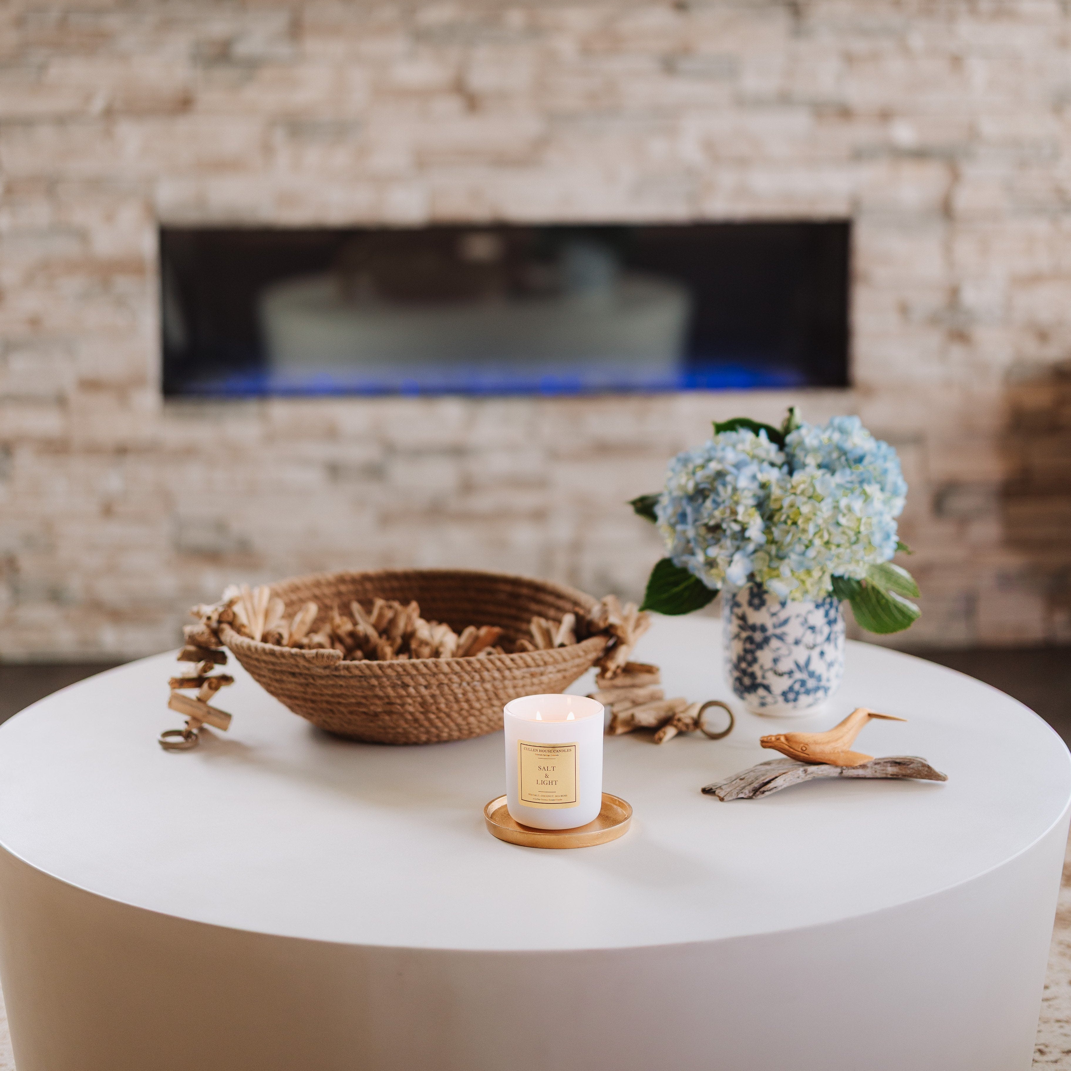 Living room with a white coffee table, decorative items, and a stone fireplace.