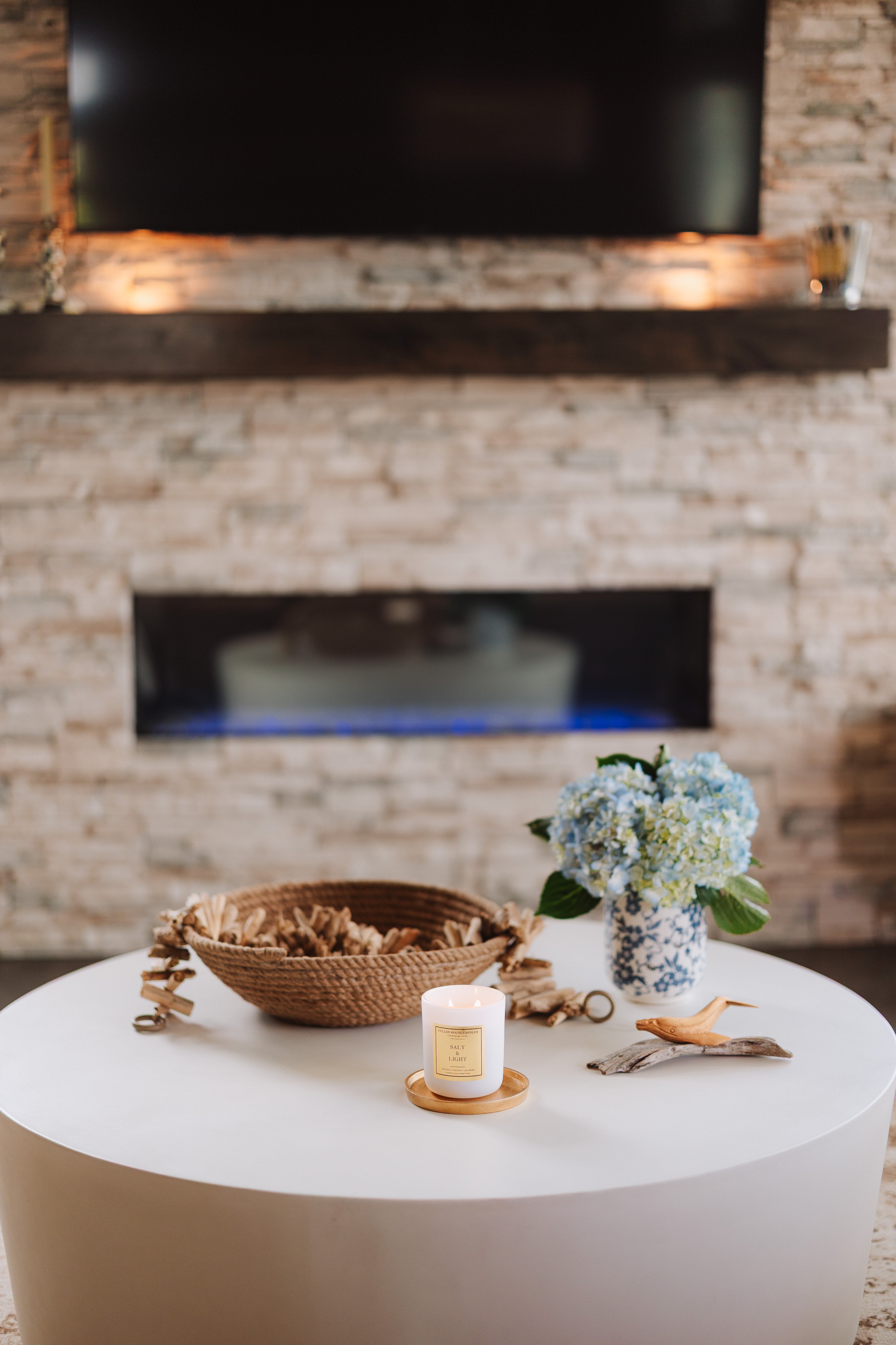 Living room with a white coffee table, decorative items, and a stone fireplace.