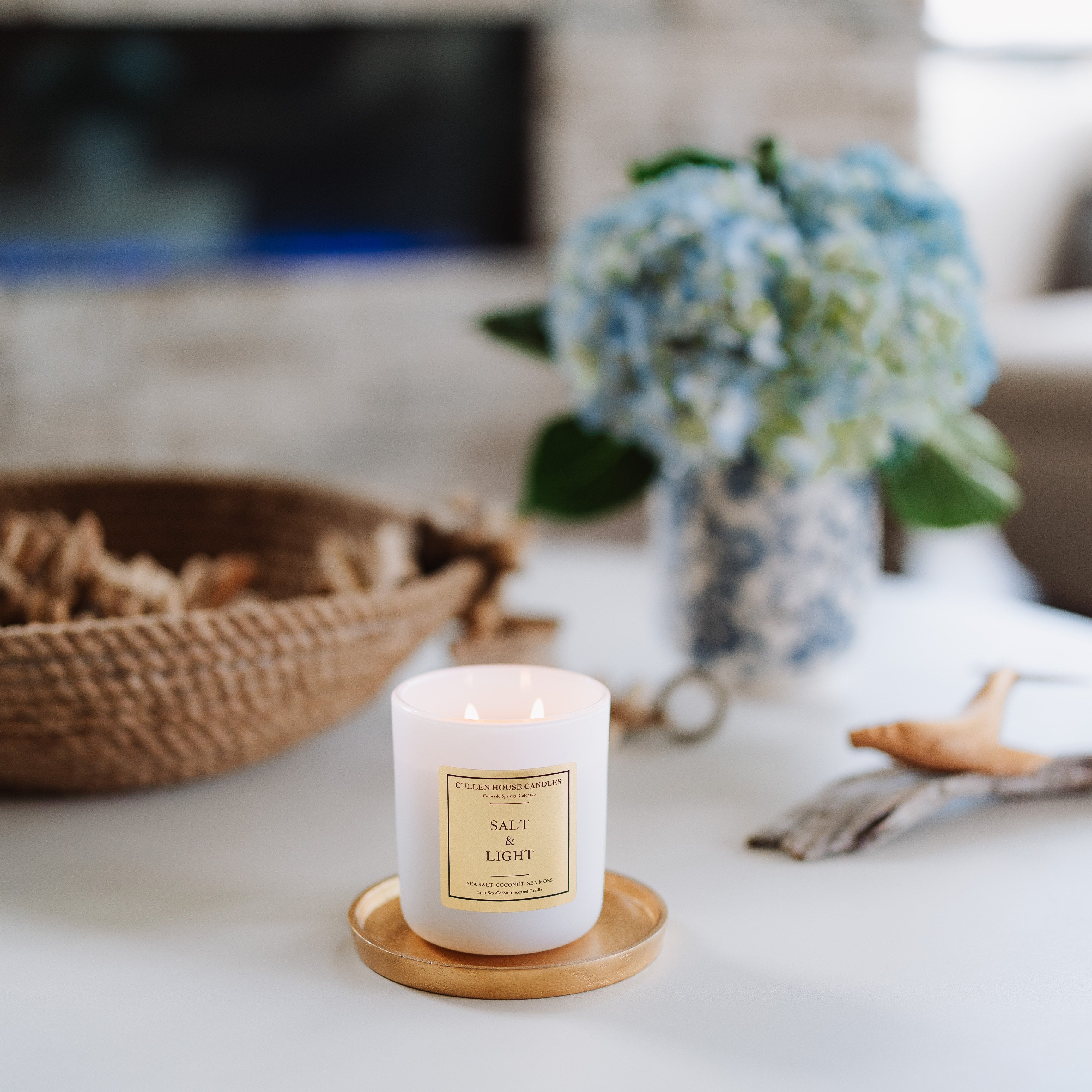 Candle on a wooden coaster with a fireplace and decorative items in the background