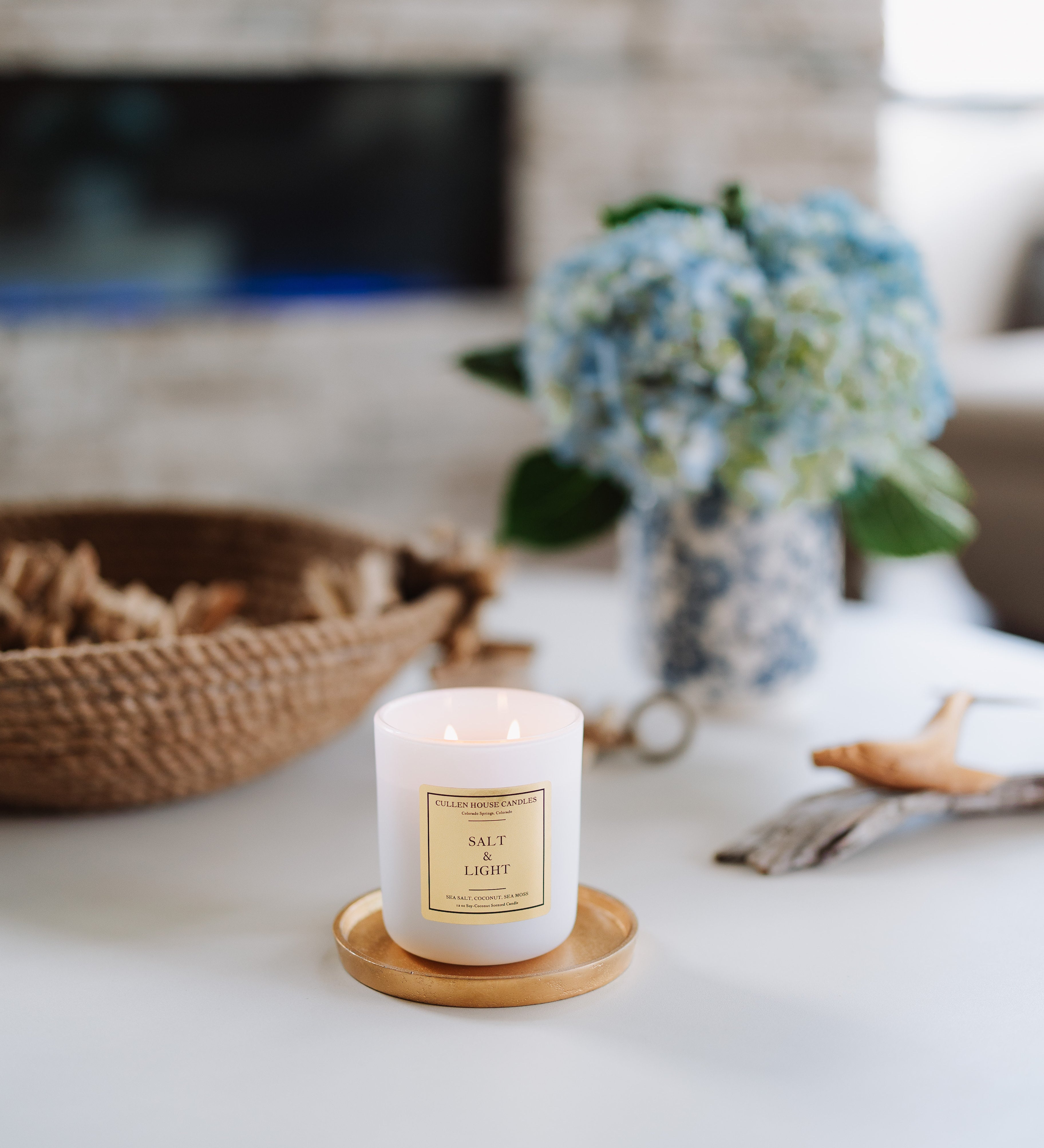 Candle on a wooden coaster with a fireplace and decorative items in the background