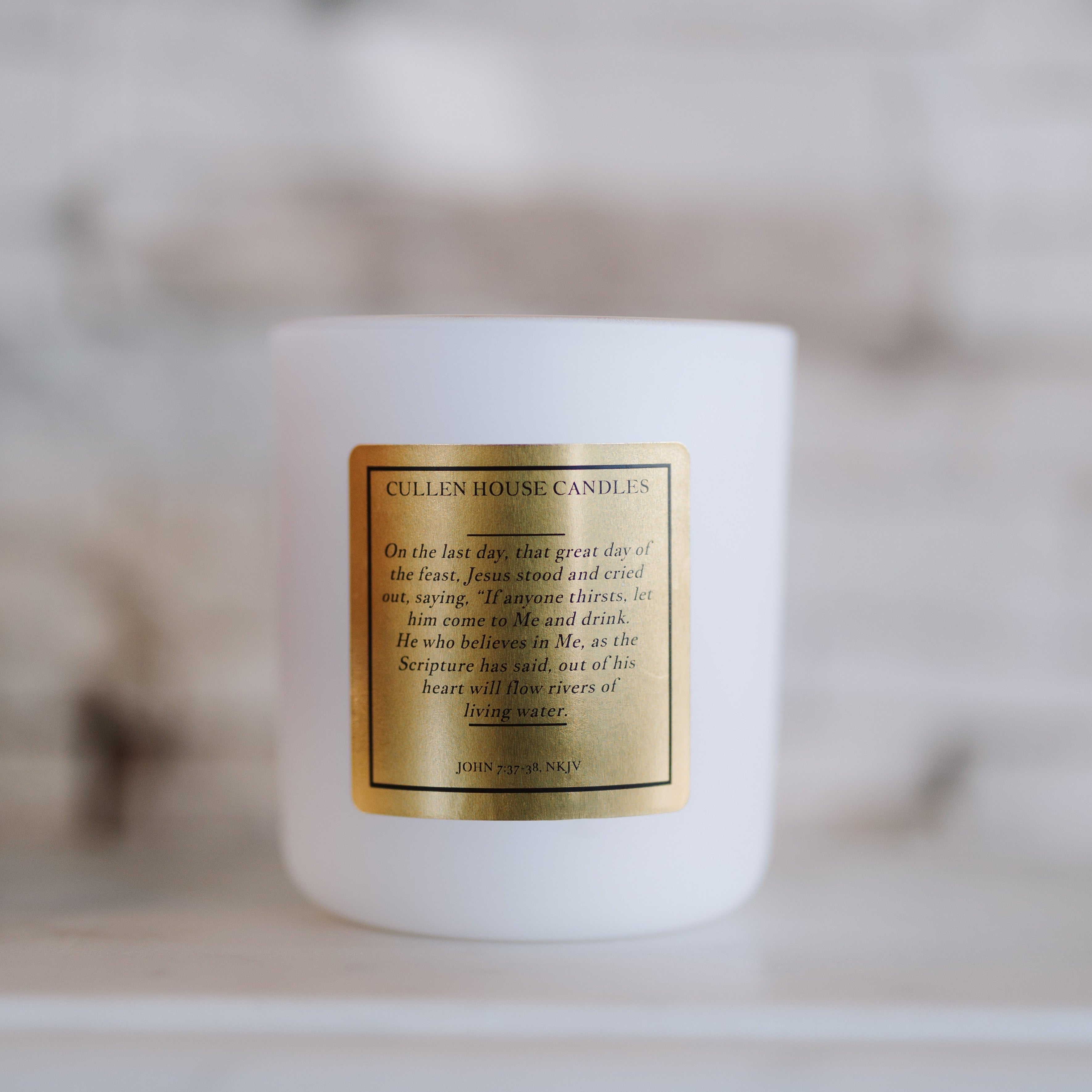 White candle with a gold label on a blurred background