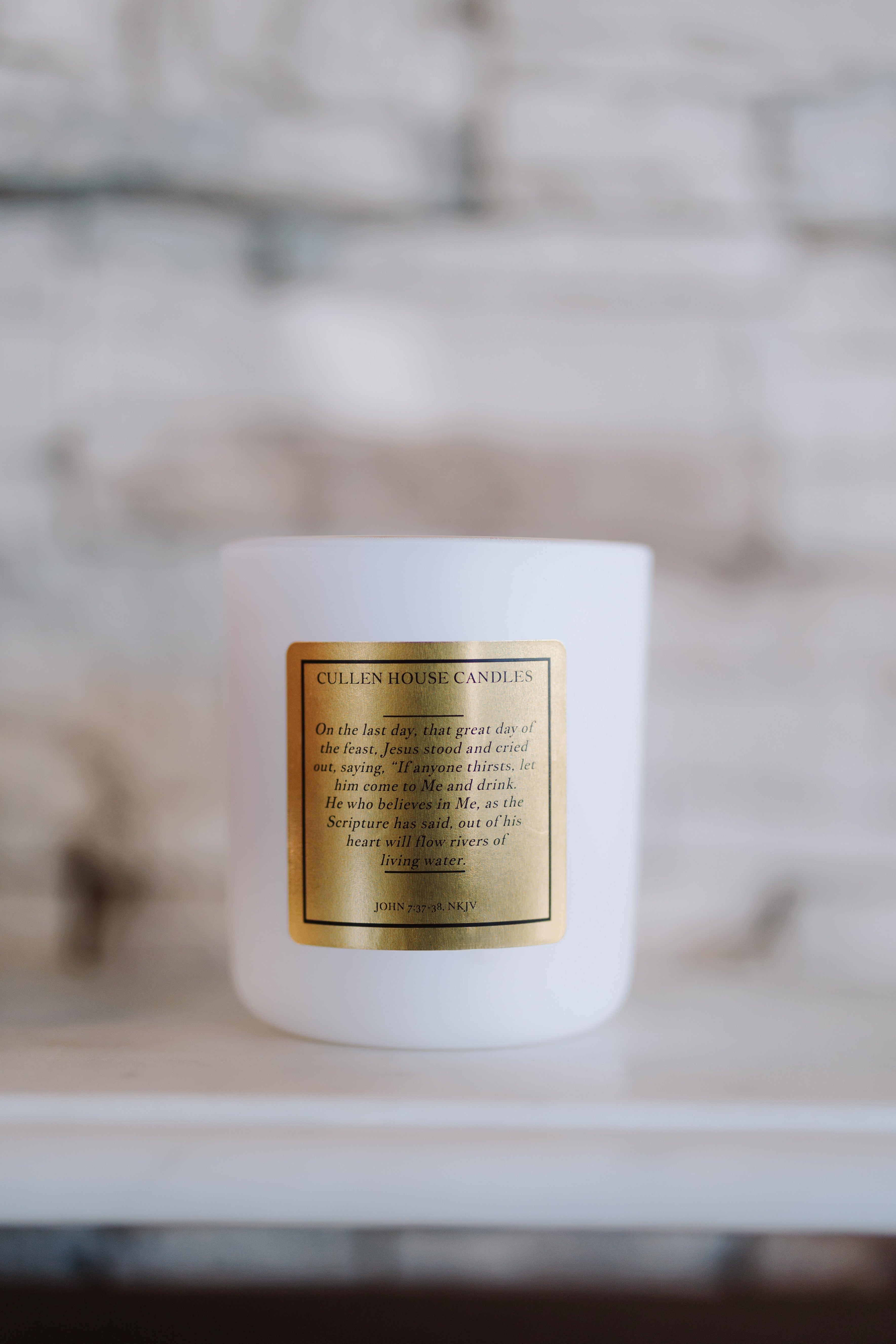 White candle with a gold label on a blurred background