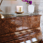 Piano with a candle and decorative flowers on a glass surface