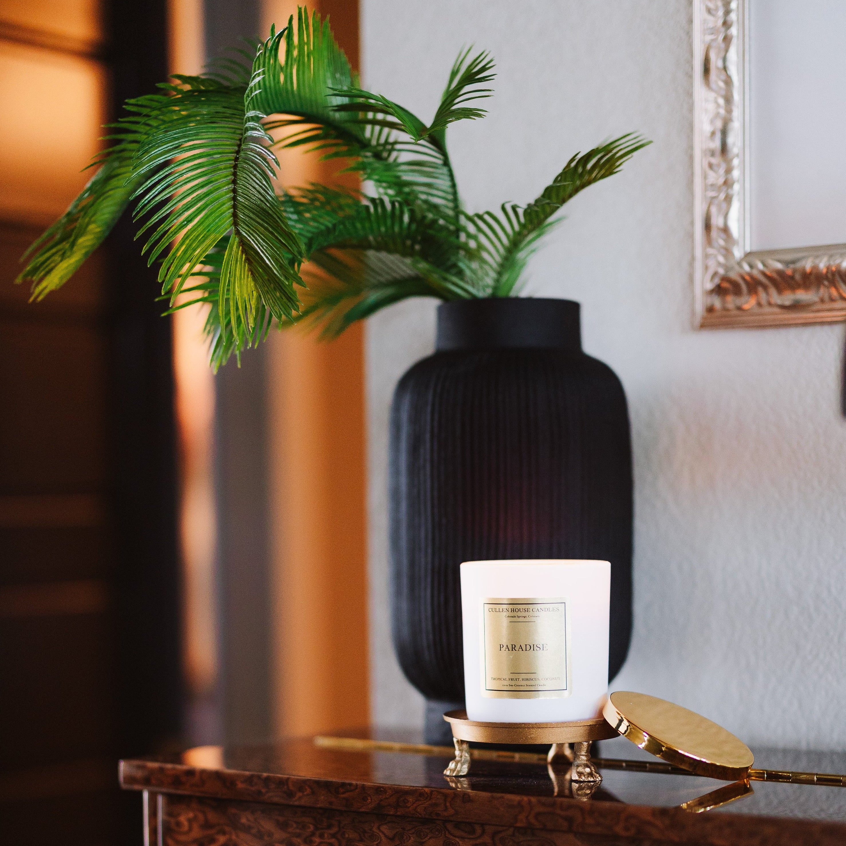 Decorative setting with a plant, vase, and candle on a wooden surface.
