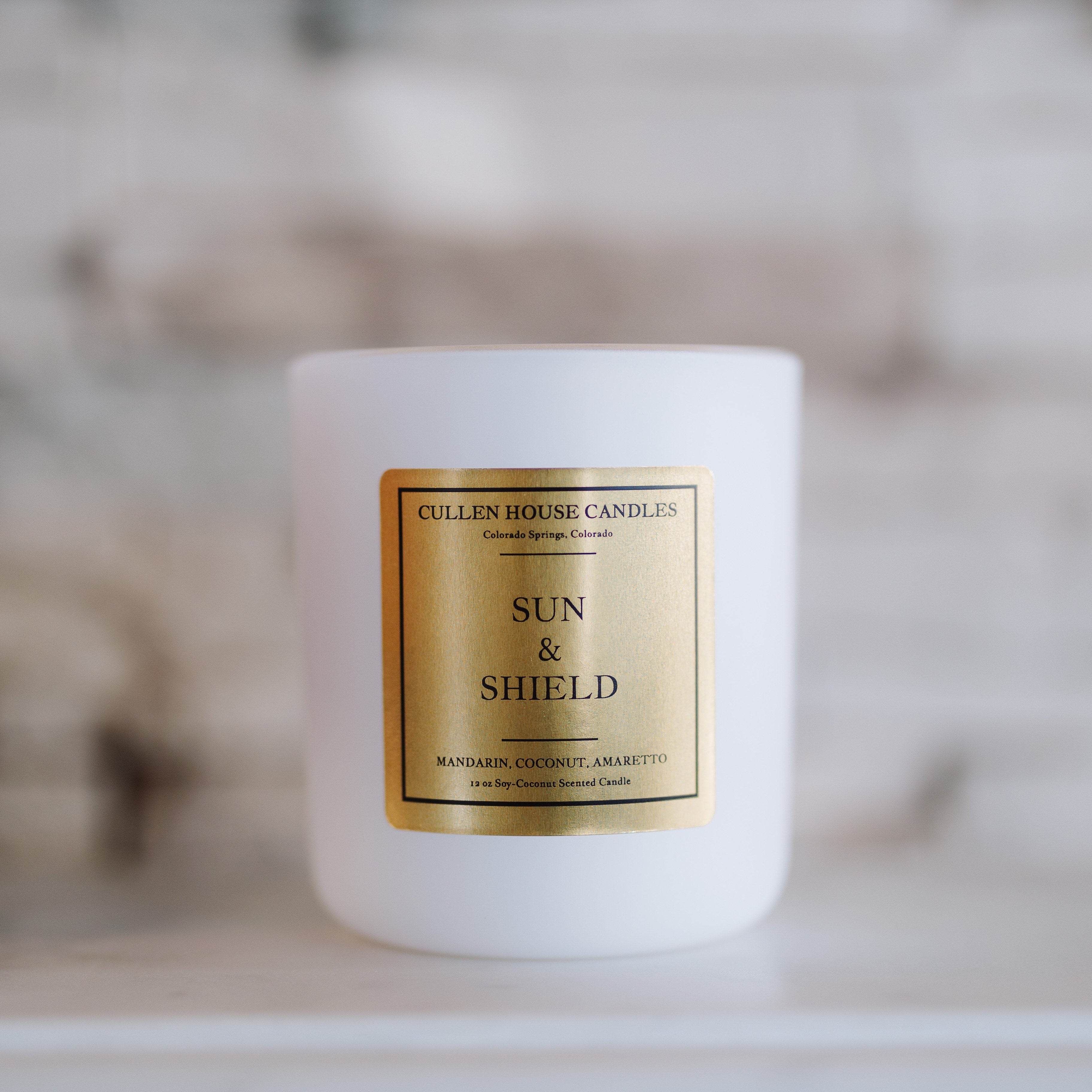 White candle with a gold label on a blurred background