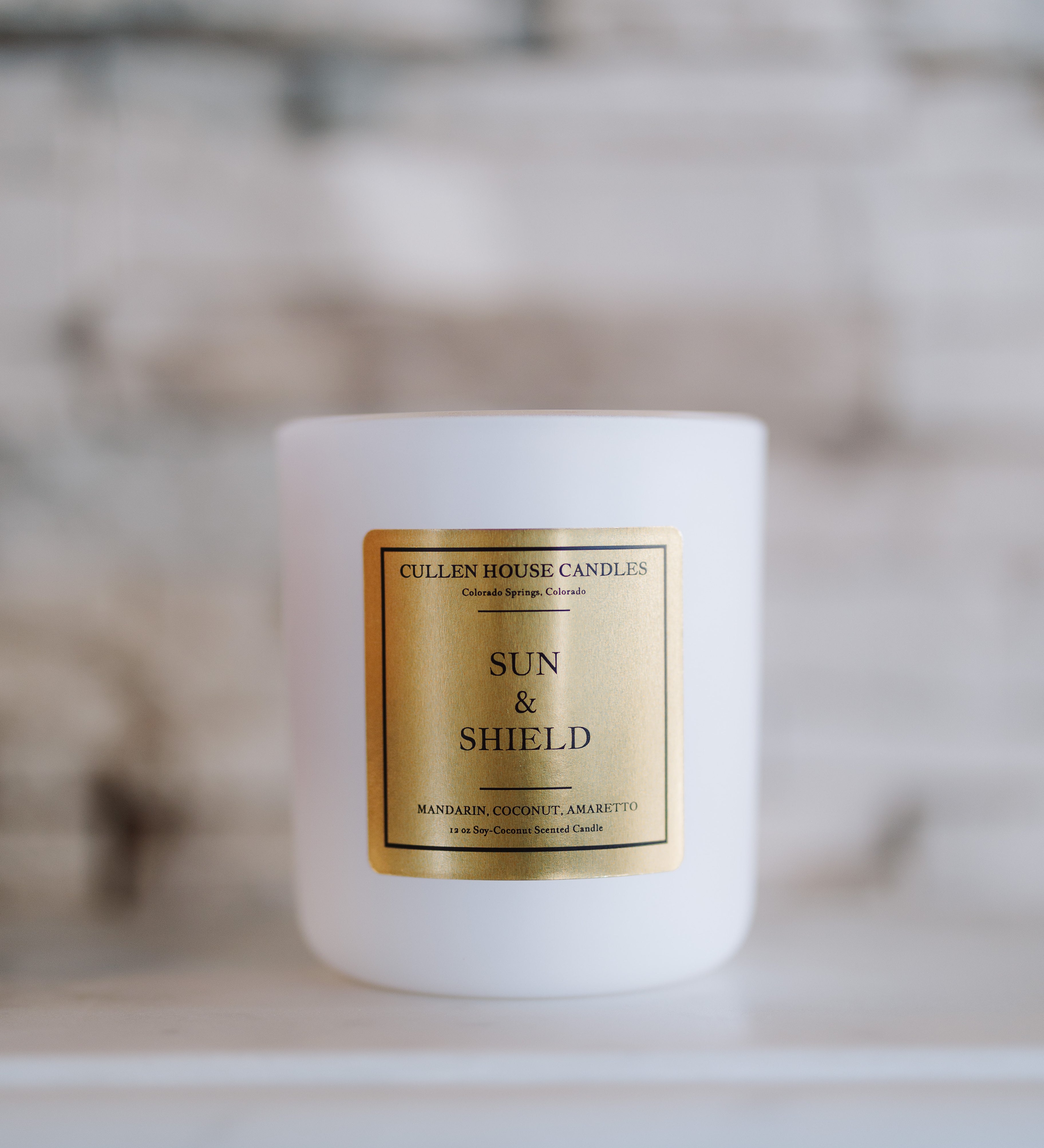 White candle with a gold label on a blurred background