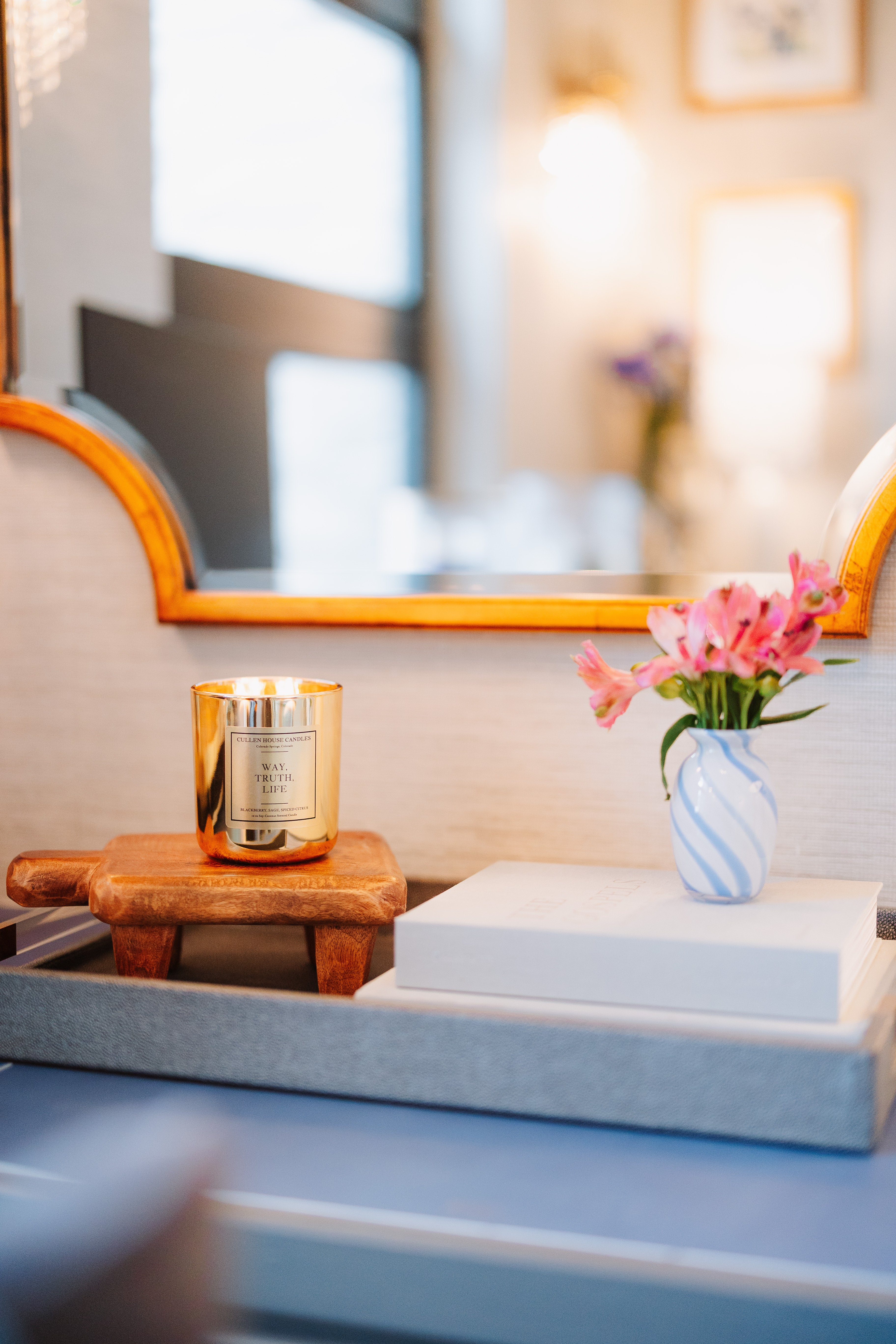 Decorative setup with a candle, flowers, and books on a surface.