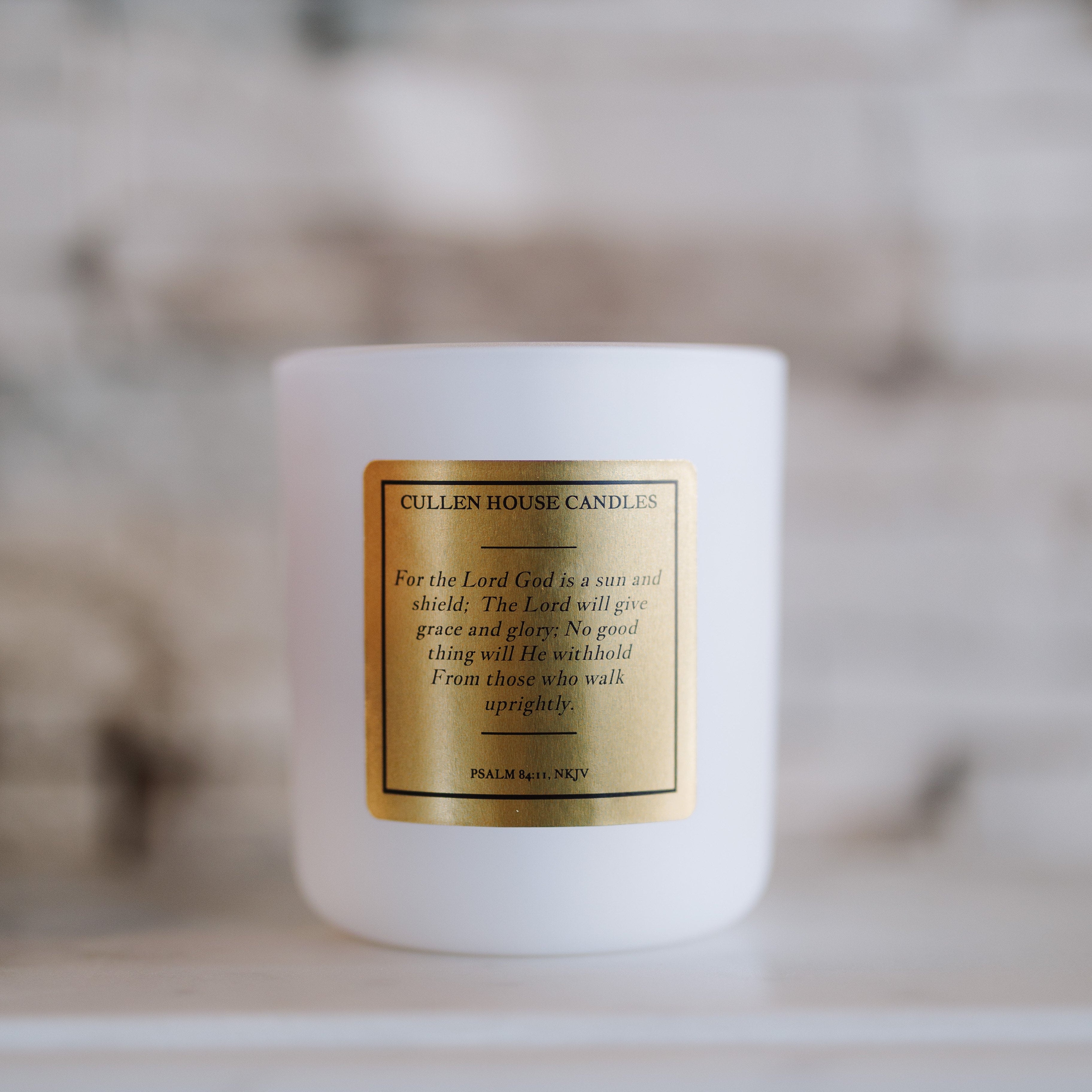 White candle with a gold label on a neutral background