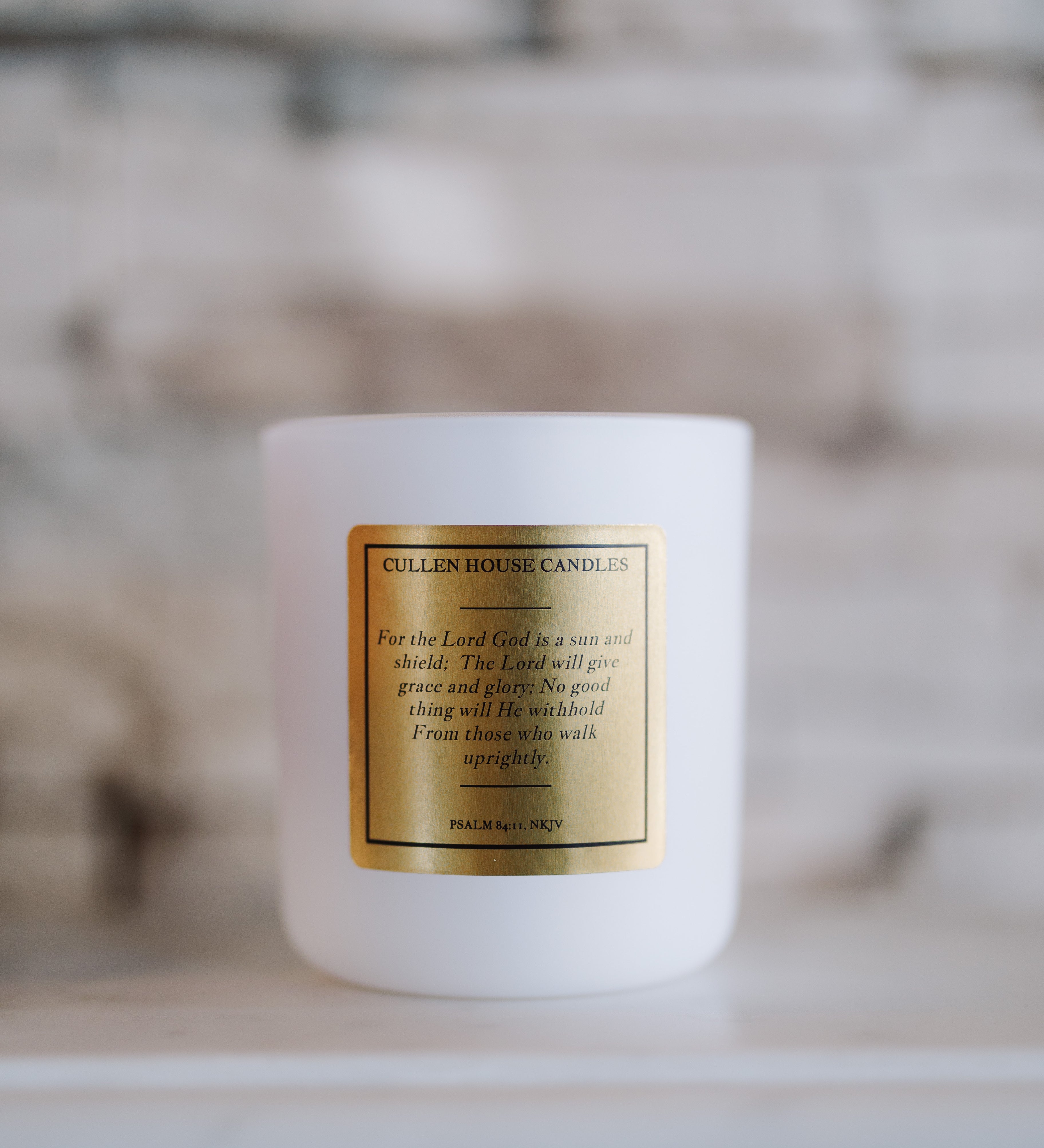 White candle with a gold label on a neutral background