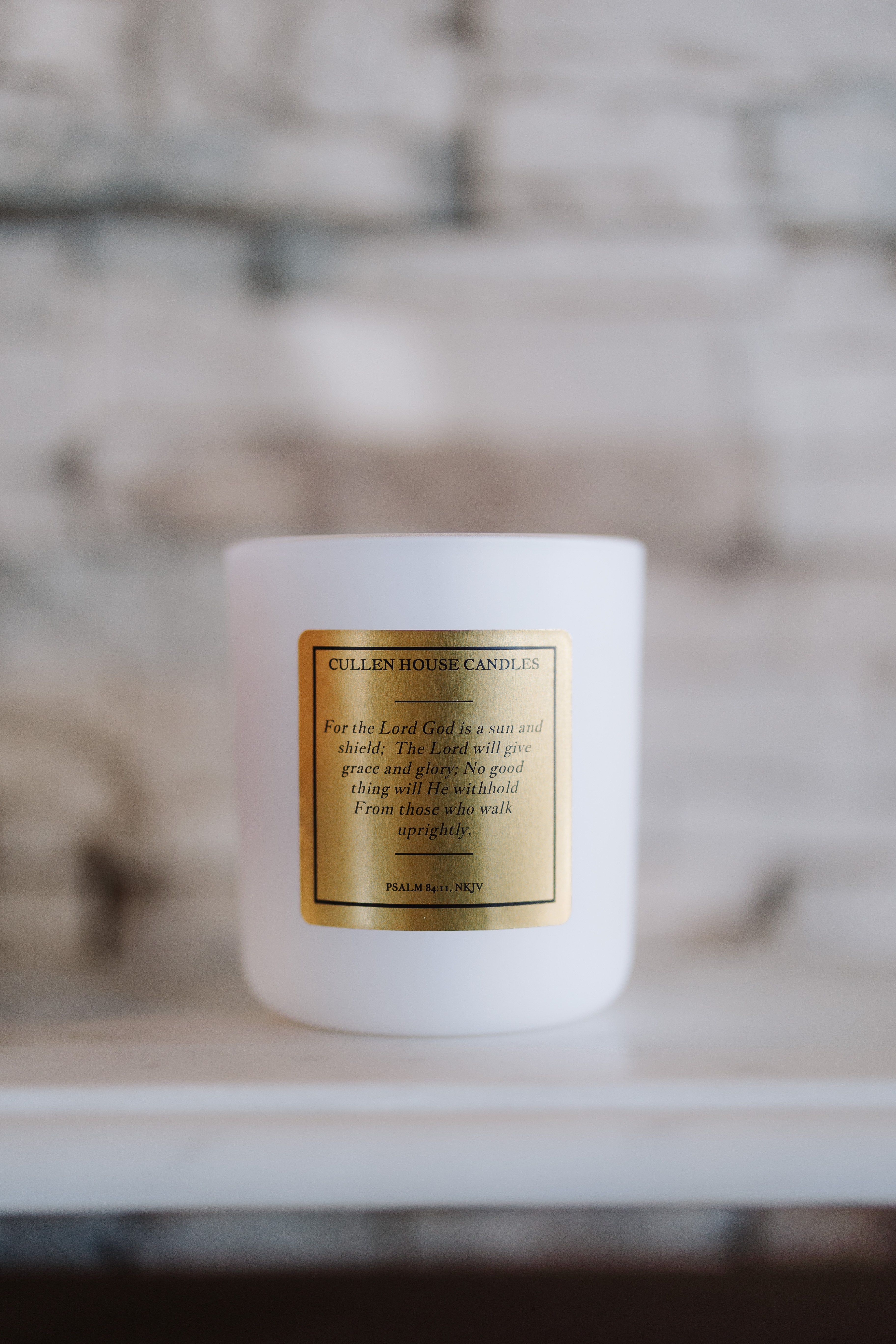 White candle with a gold label on a neutral background