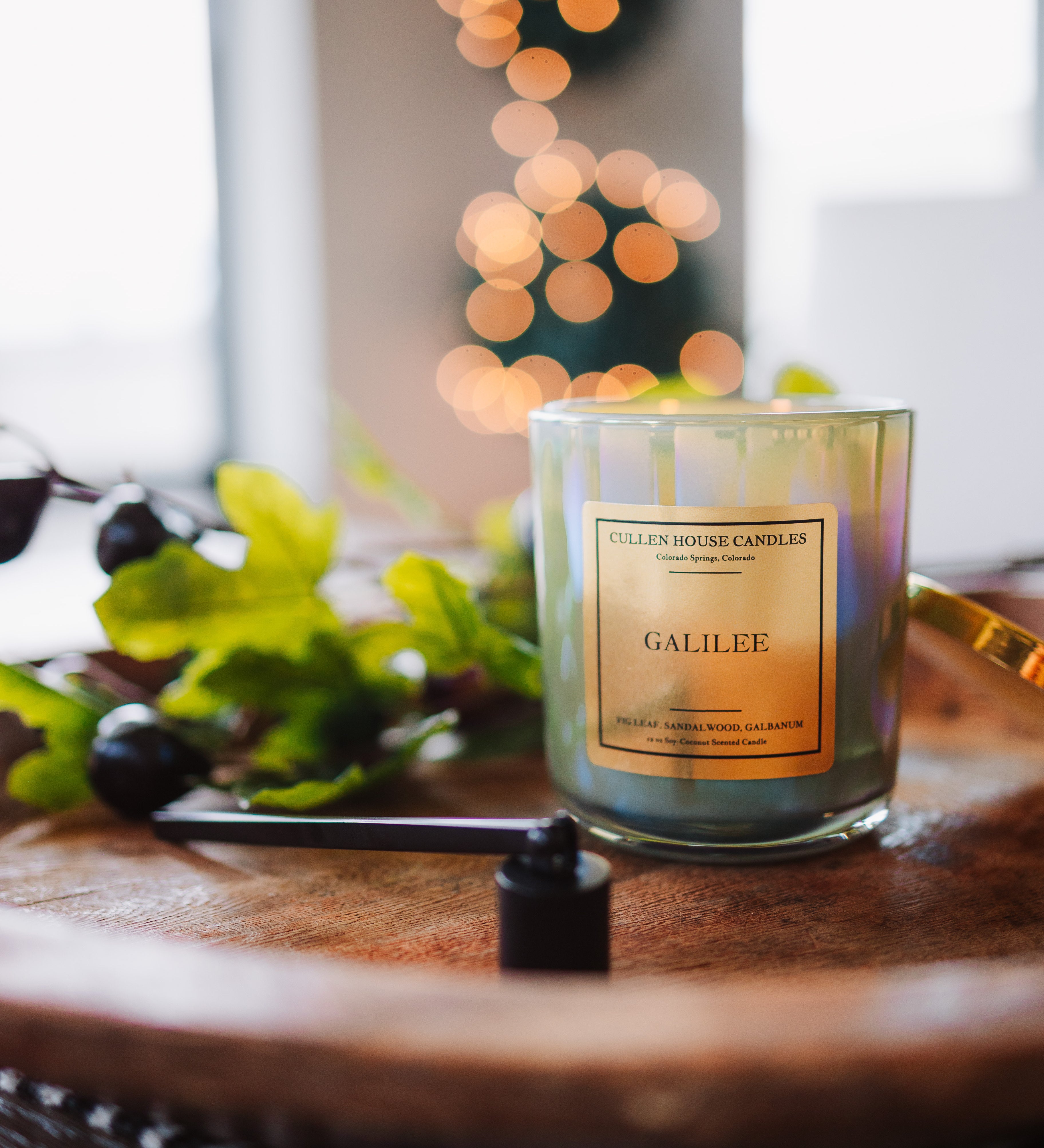Candle labeled 'Galilee' on a wooden surface with blurred lights in the background