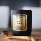 Black candle labeled 'The Chosen' on a wooden surface with a blurred background